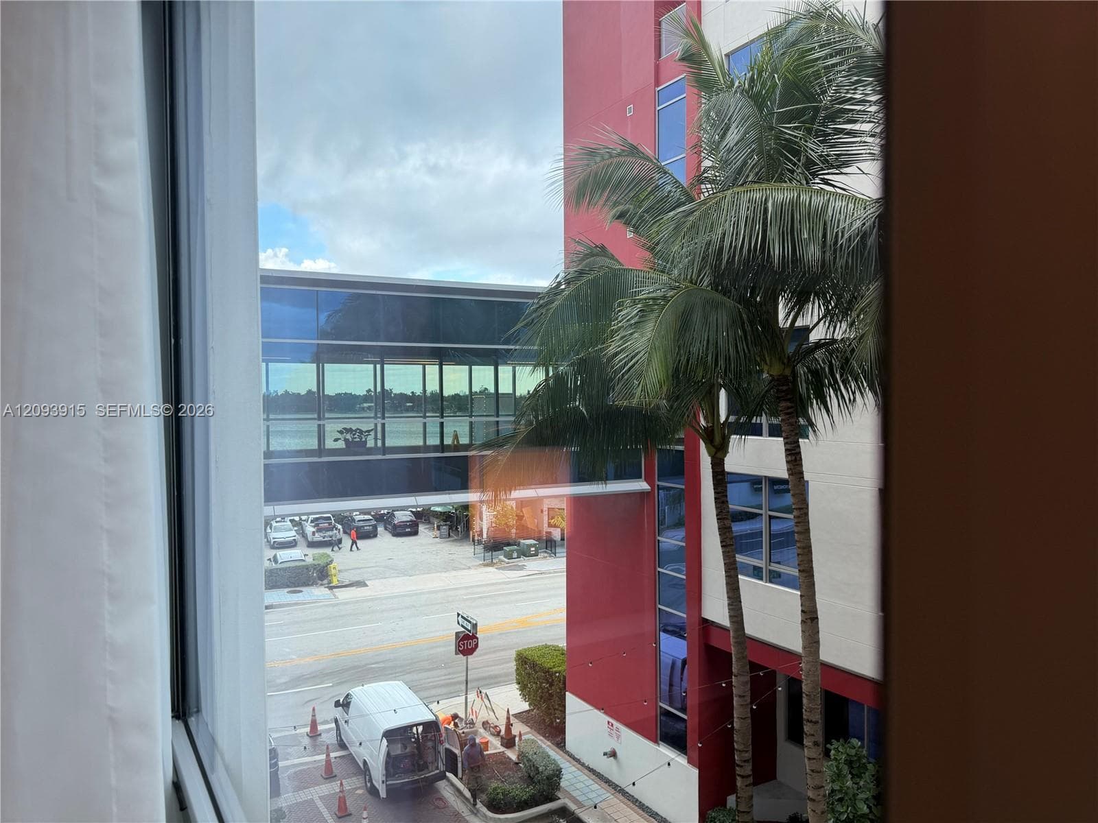 Large-pane glass window featuring an exterior in perspective of a glass-enclosed skybridge and mature palm trees .