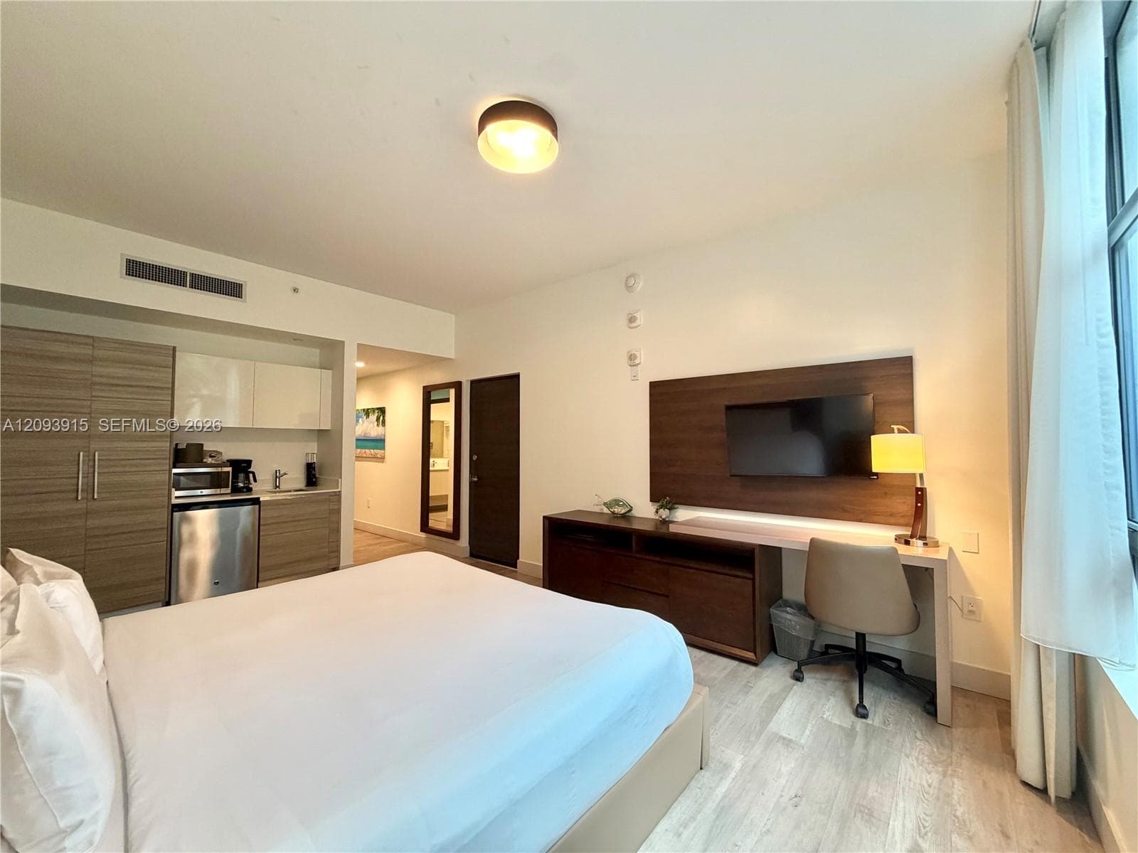 Kitchenette featuring light-toned wood-finish cabinetry, stainless steel mini-refrigerator, and white upper cabinets
