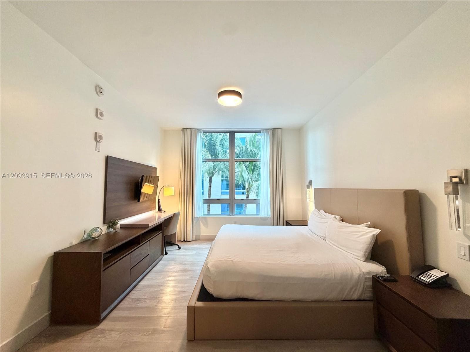 Floor-to-ceiling window with natural light, integrated wood-finish wall paneling, built-in media cabinetry, wood-finish flooring, and recessed ceiling lighting
