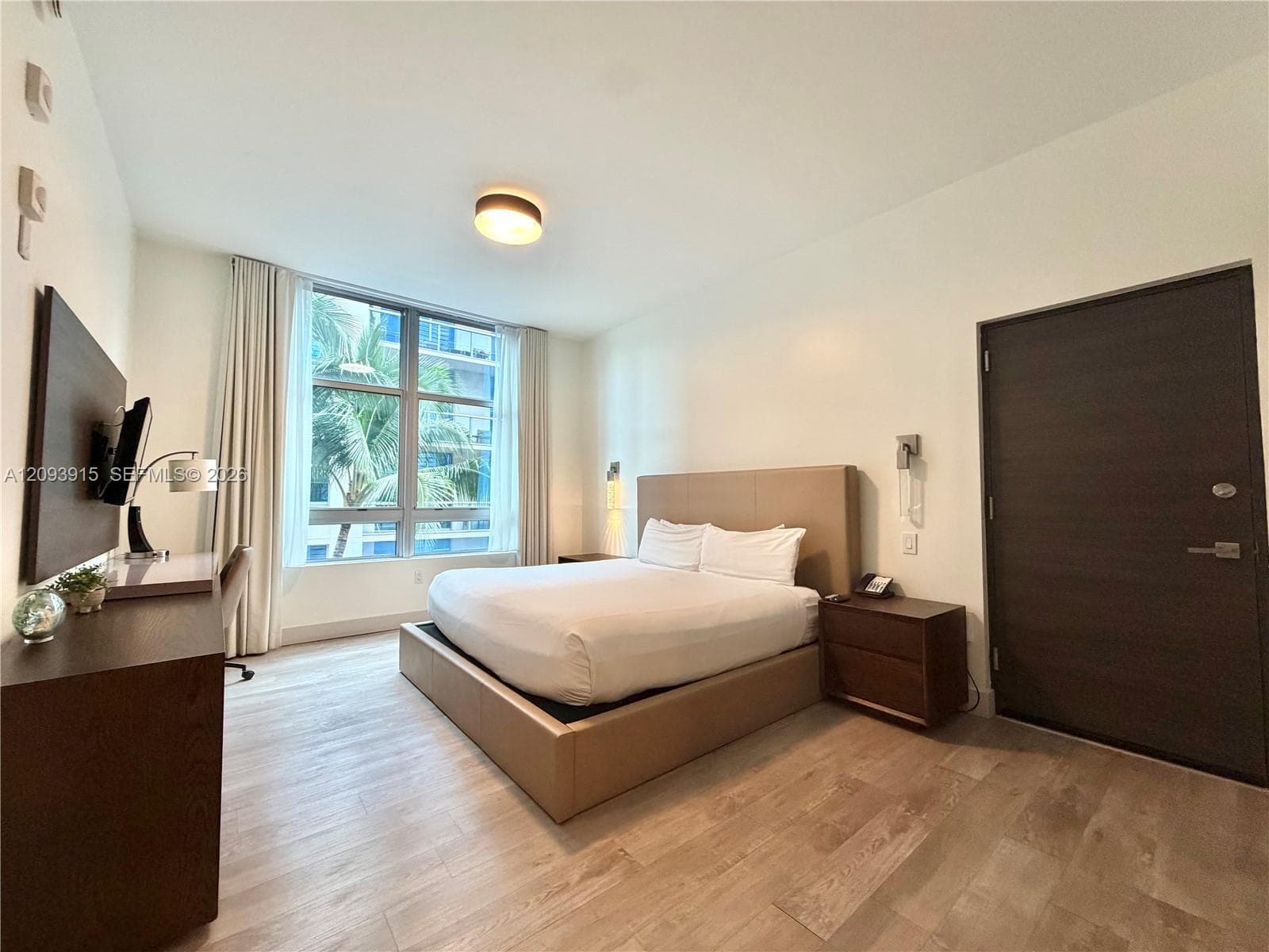 Floor-to-ceiling windows with full-length drapery, wood-finish flooring, and solid-core interior door