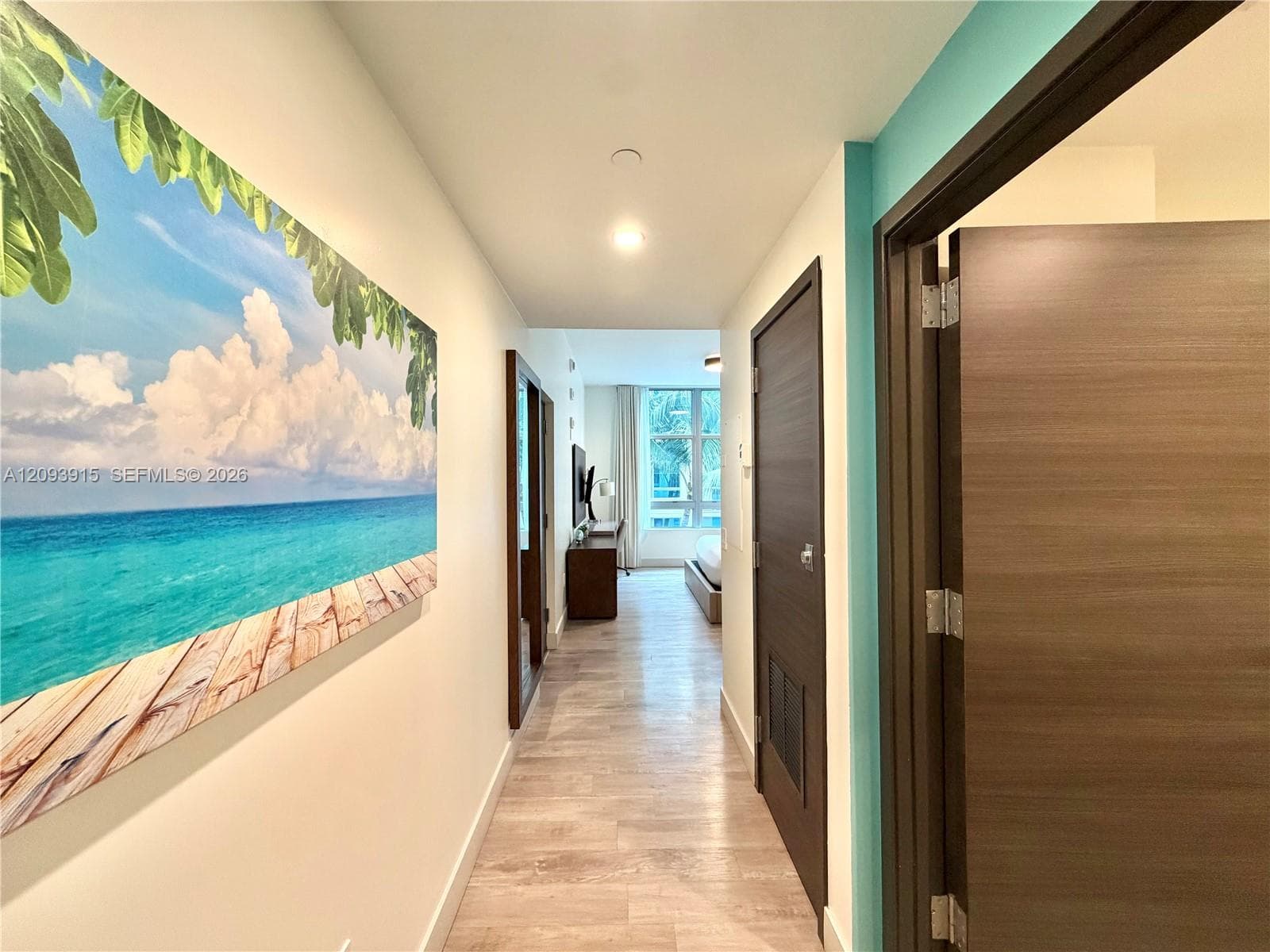 Hallway featuring wood-finish flooring, full-height solid-core doors with horizontal grain, and smooth finish ceiling with recessed lighting