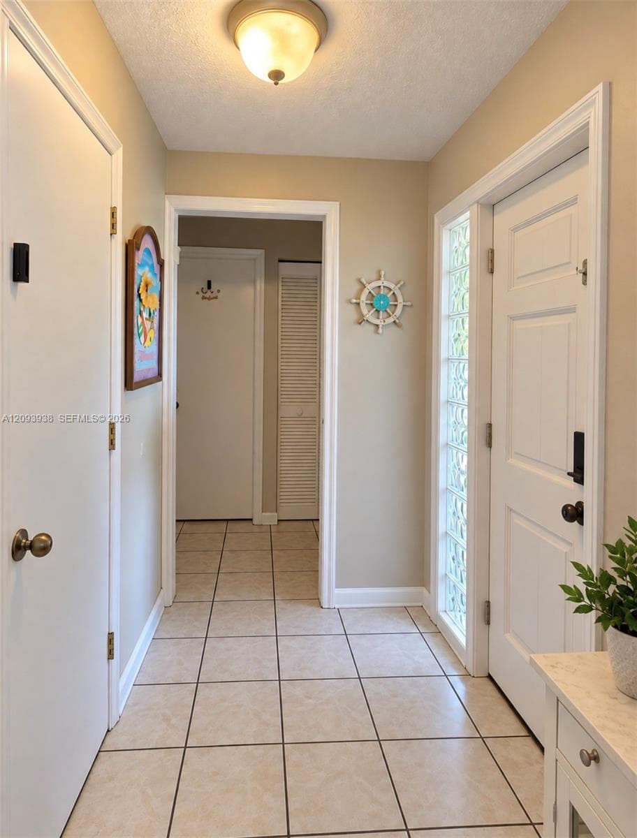 Foyer featuring tiled flooring, a glass block sidelight, six-panel interior doors, and a flush-mount ceiling light fixture