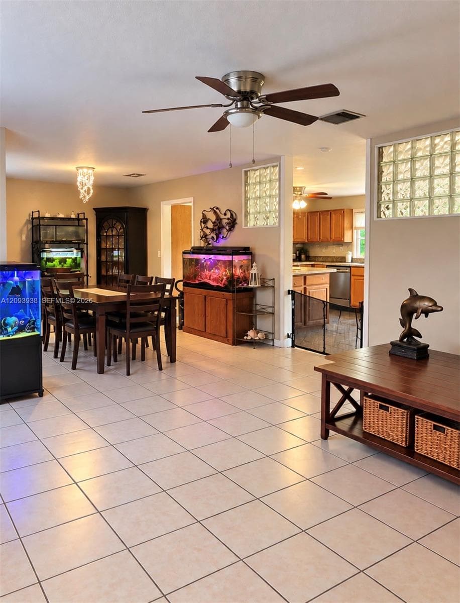 Open-concept interior featuring light-toned tile flooring, inset glass block wall panels, and a central ceiling fan with integrated lighting