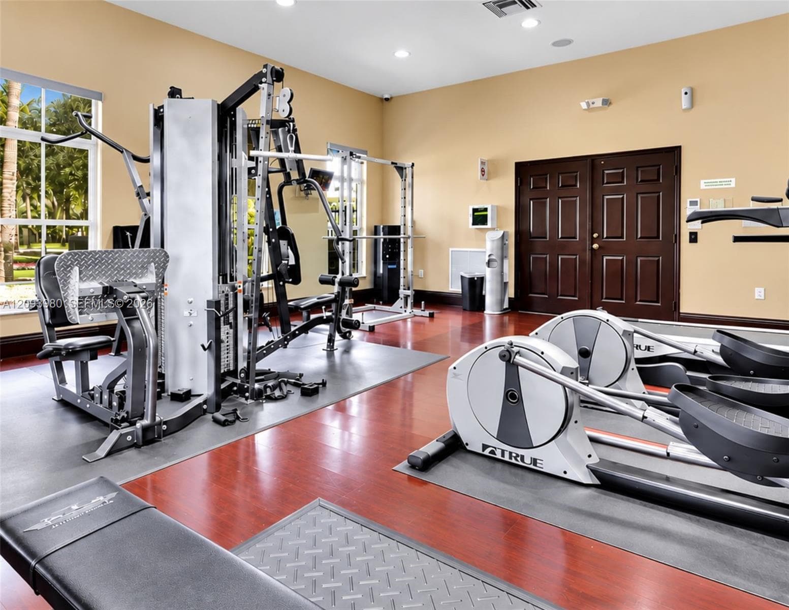 Fitness center featuring wood-finish flooring, recessed ceiling lighting, and multi-panel solid wood double doors