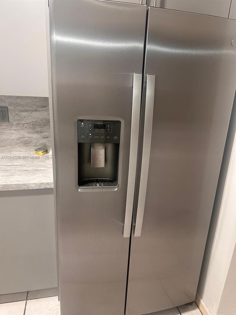 Stainless steel side-by-side refrigerator featuring an integrated water and ice dispenser