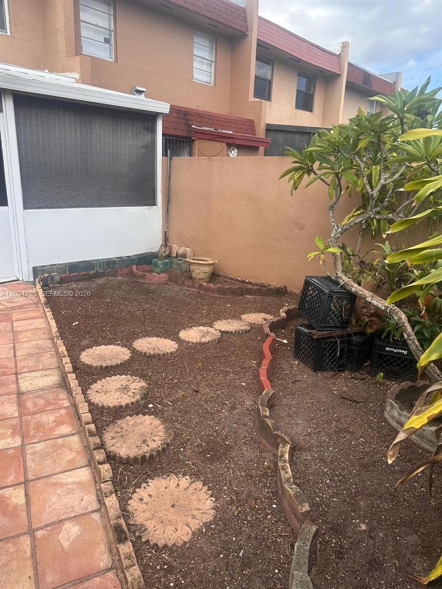 Enclosed patio featuring tile flooring, concrete paver pathway, and masonry perimeter wall