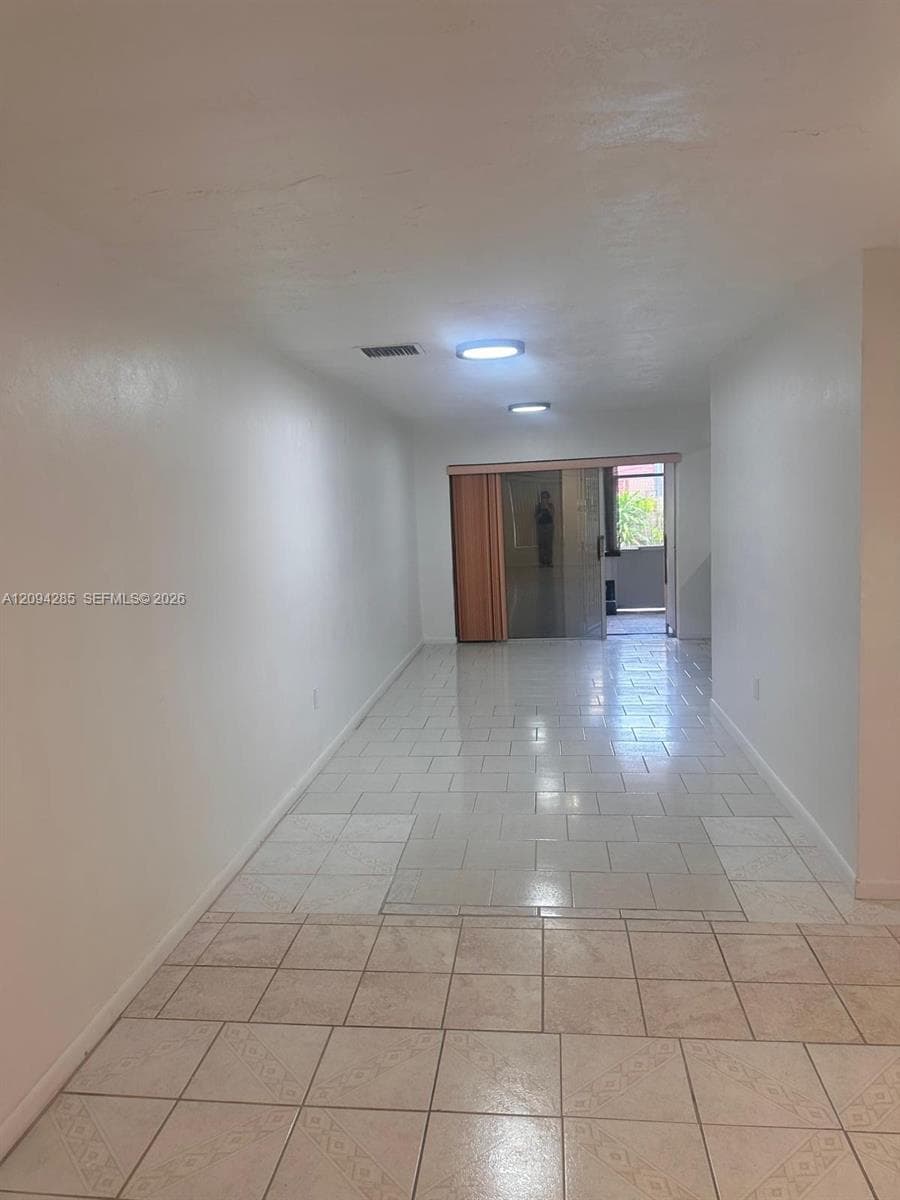 Interior space featuring neutral wall tones, large-format tile flooring, recessed LED lighting, and a sliding glass door providing external access