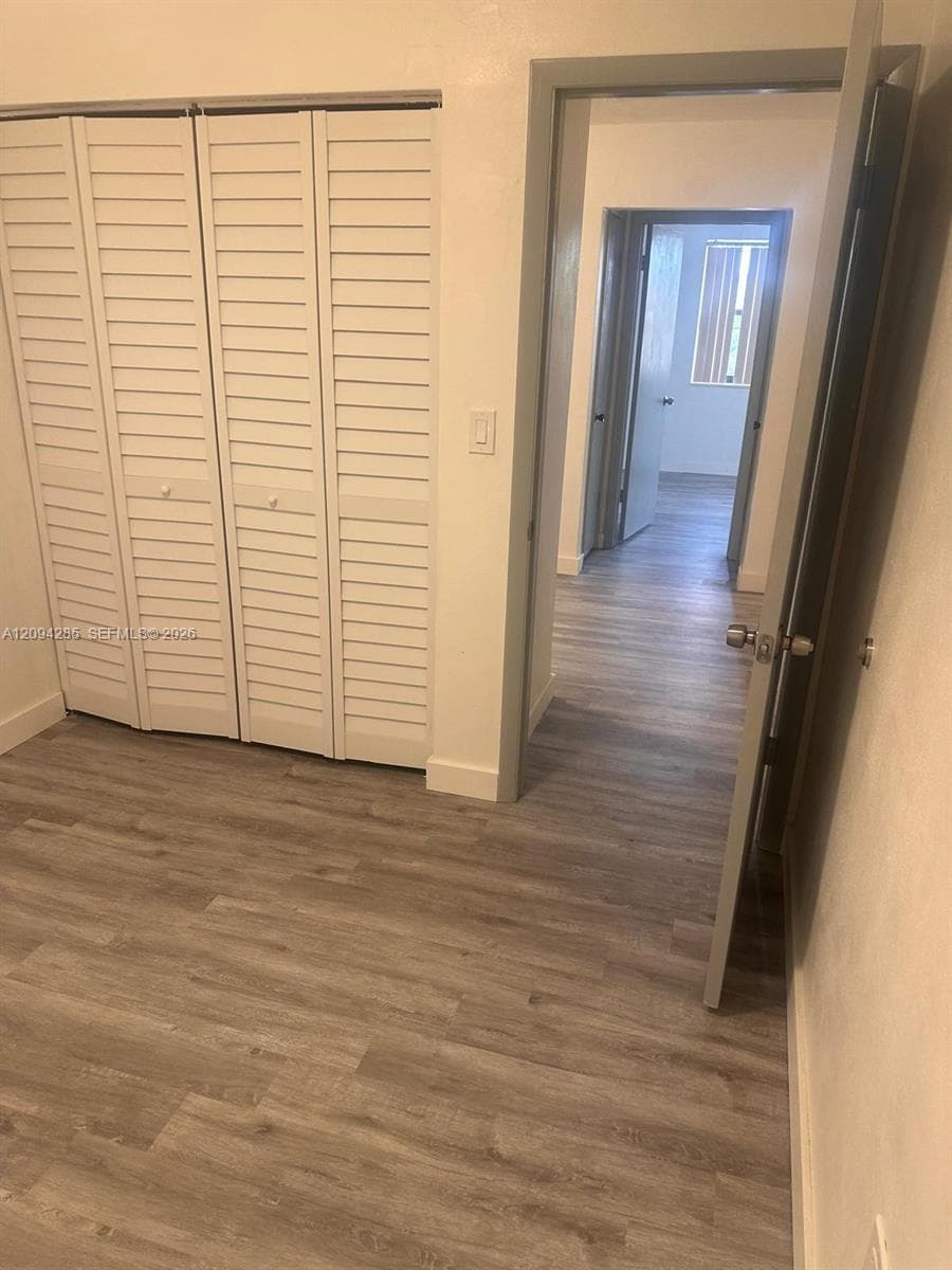 Wood-finish flooring throughout, white louvered bifold closet doors, and interior paneled doors