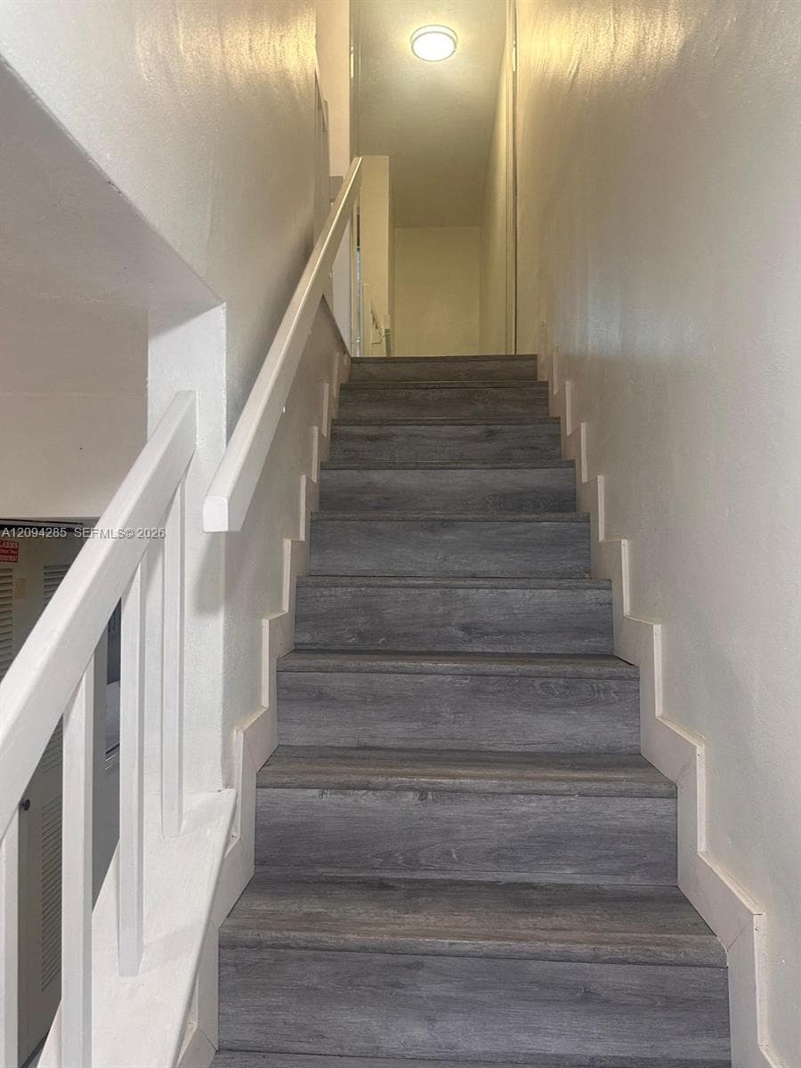 Staircase featuring wood-finish treads, white stringers, and a white handrail with matching balusters