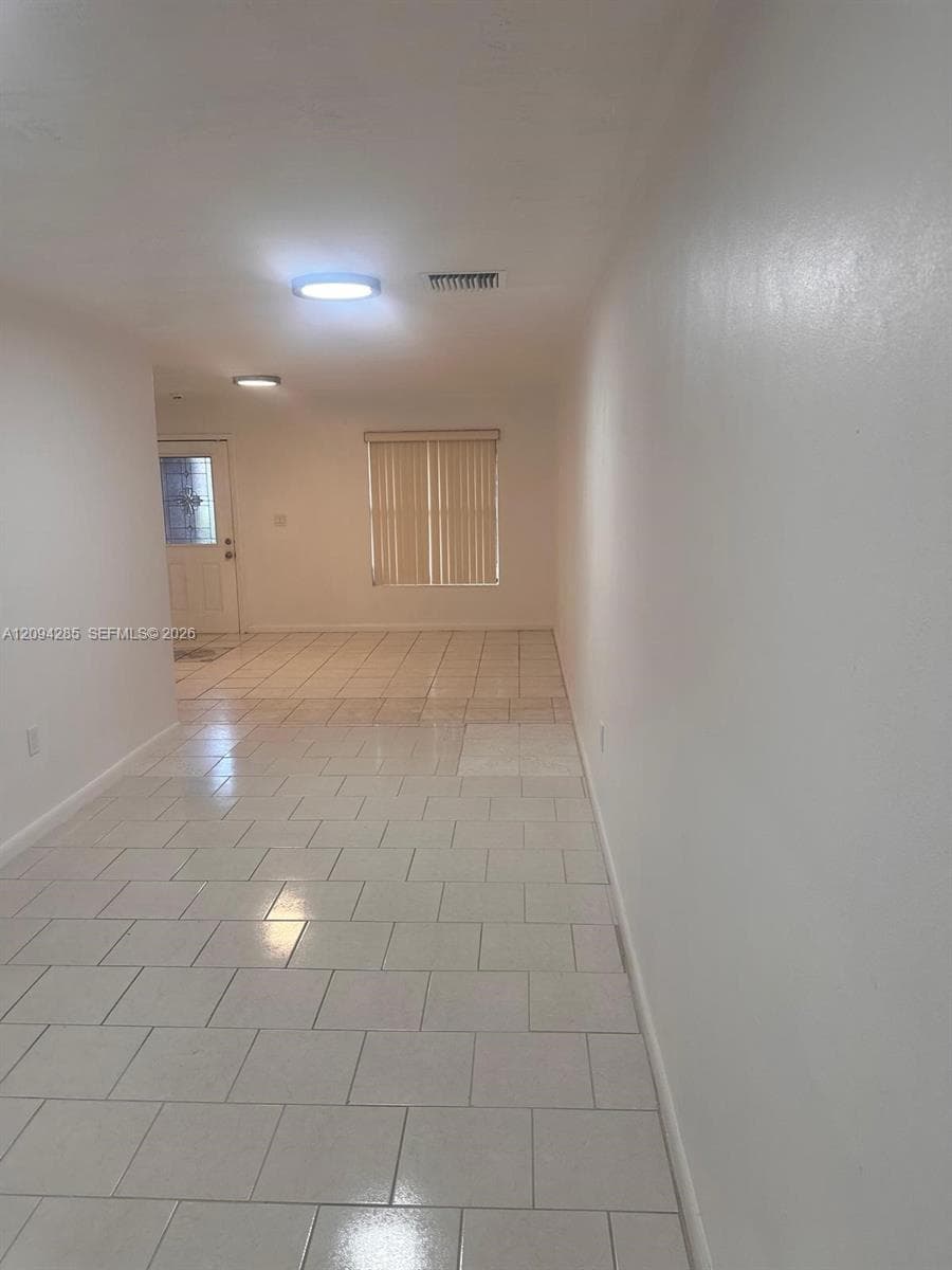 Neutral-toned ceramic tile flooring, flush-mount circular ceiling lighting, and vertical window blinds