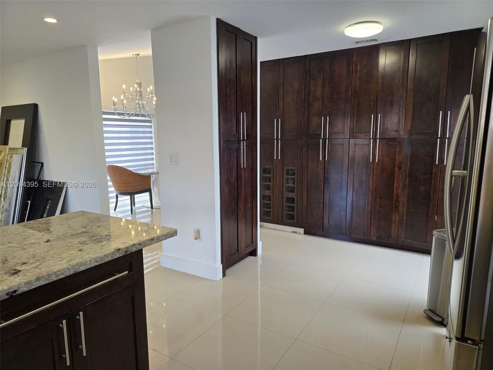 Custom dark wood cabinetry, light stone countertops, built-in wine storage, and high-gloss tile flooring