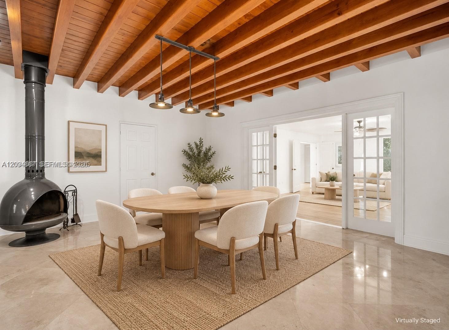Exposed wood beam ceiling, freestanding matte black metal fireplace, stone-finish flooring, and multi-pane French doors with white trim