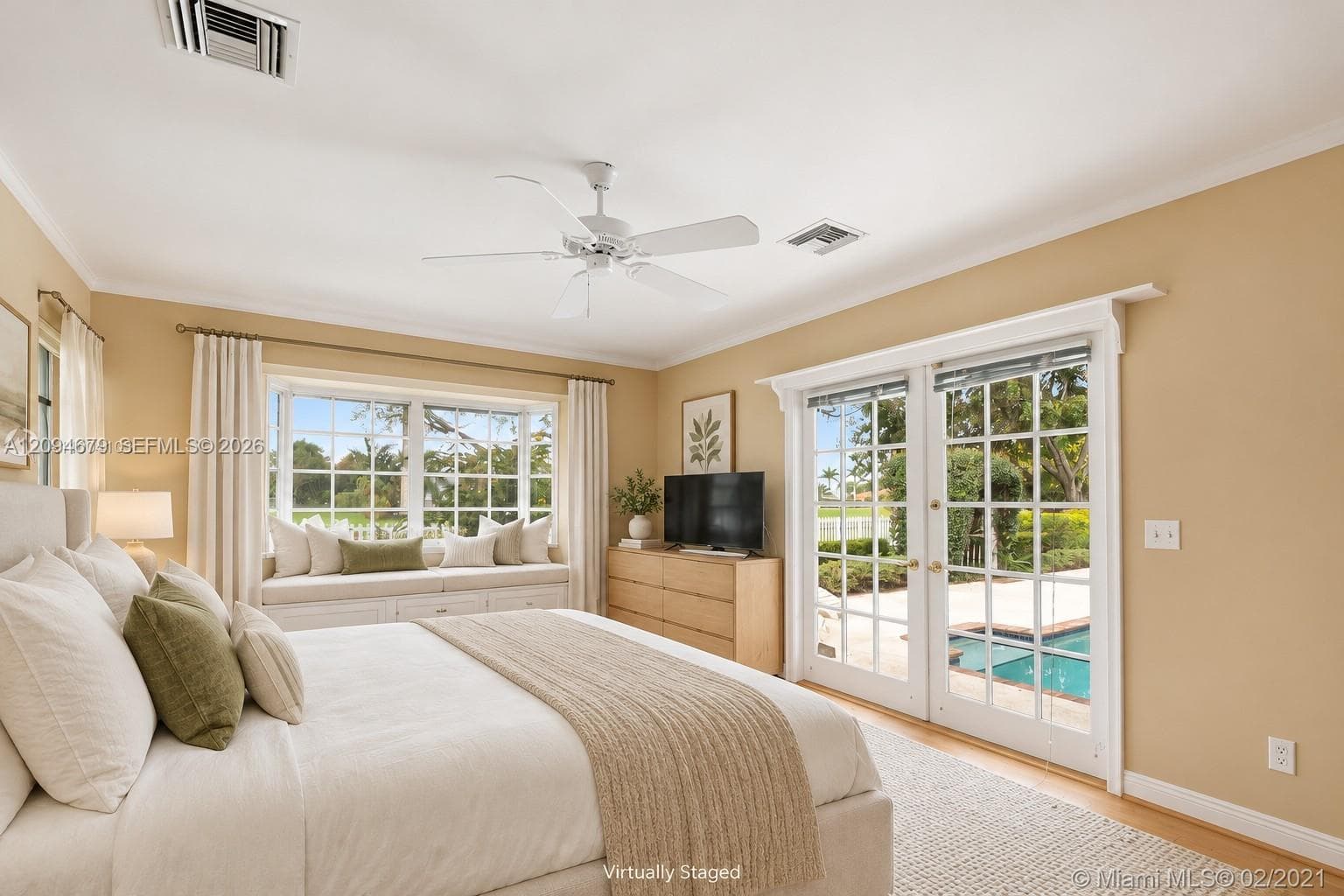 Room featuring large windows with a built-in window seat, double-door glass entry to the exterior, crown molding, and a central ceiling fan