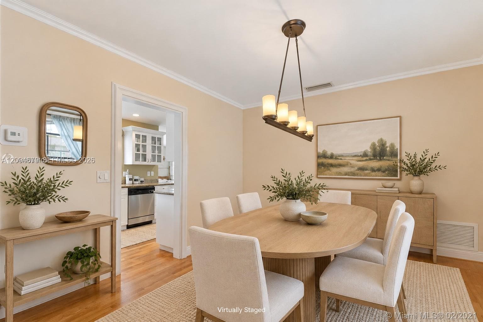 Dining area featuring wood-finish flooring, crown molding, and a four-light linear pendant fixture