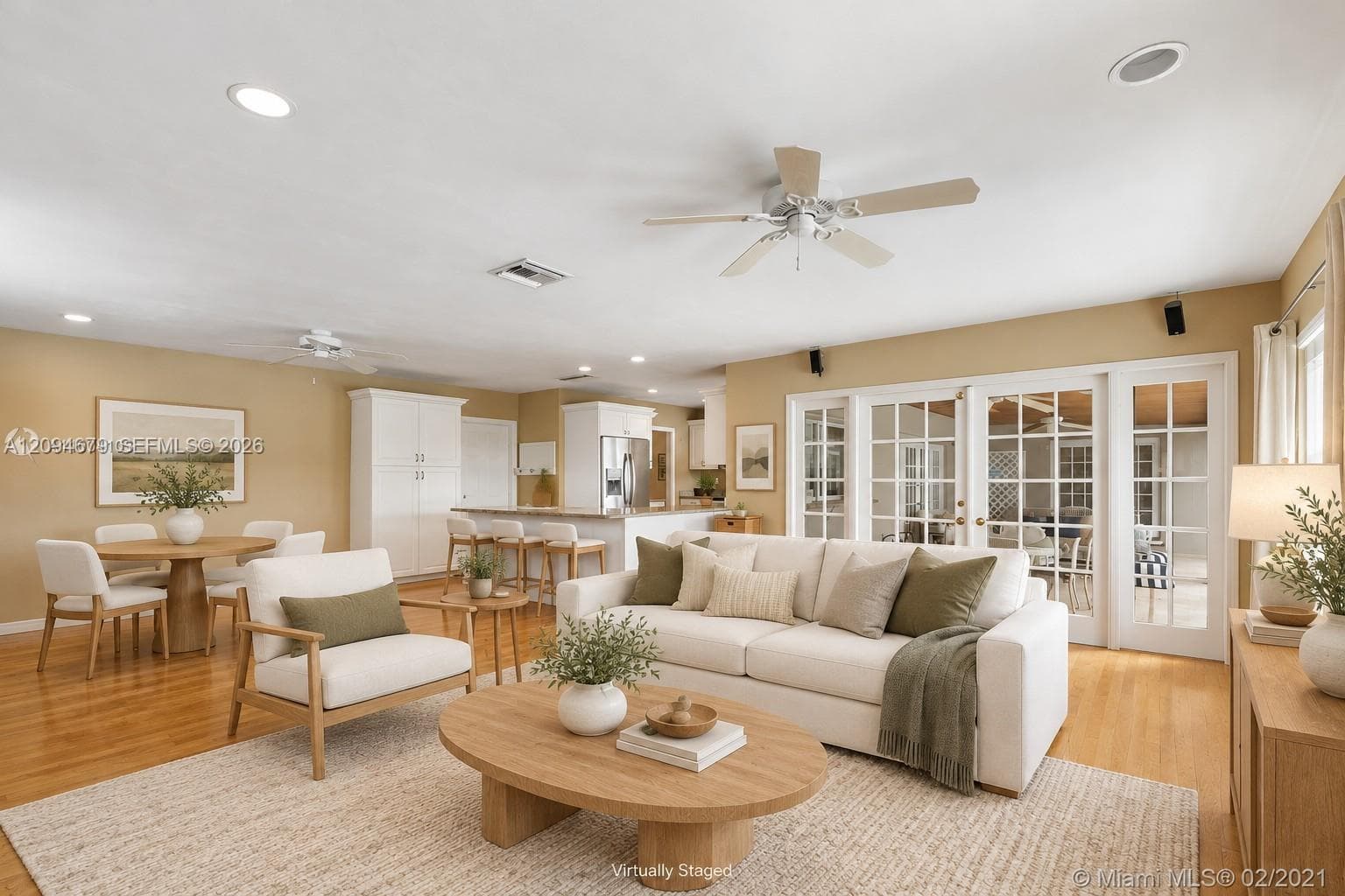 Open-concept living space featuring wood-finish flooring, recessed lighting, ceiling fans, and a set of multi-panel glass patio doors