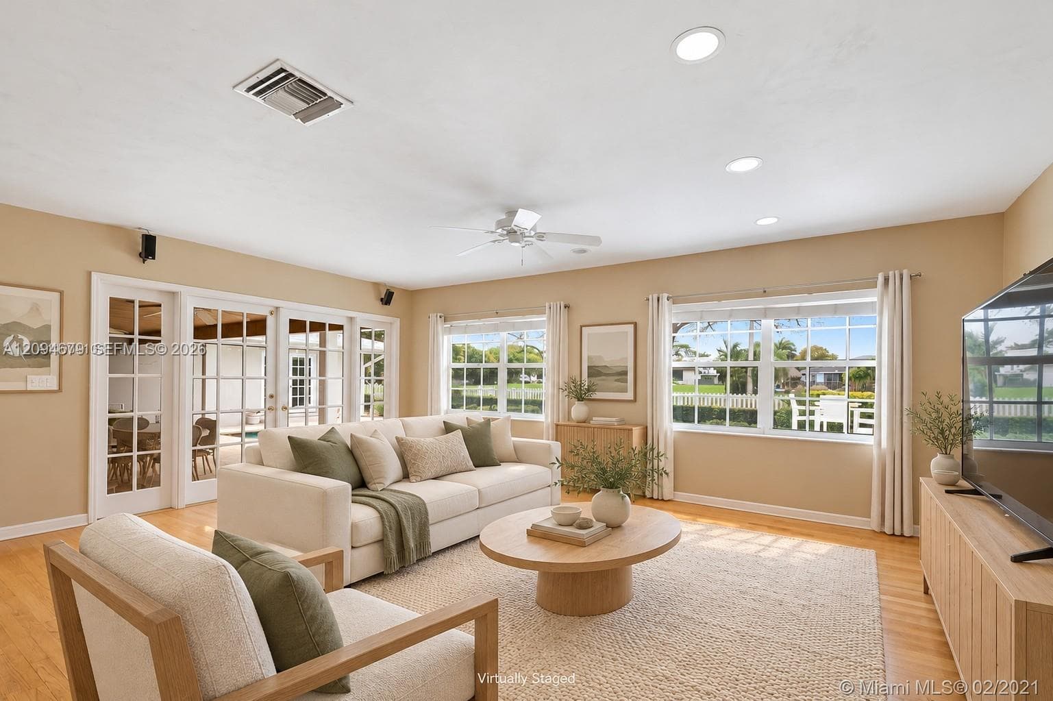 Living area featuring wood-finish flooring, recessed lighting, ceiling fan, and multi-pane windows providing natural light