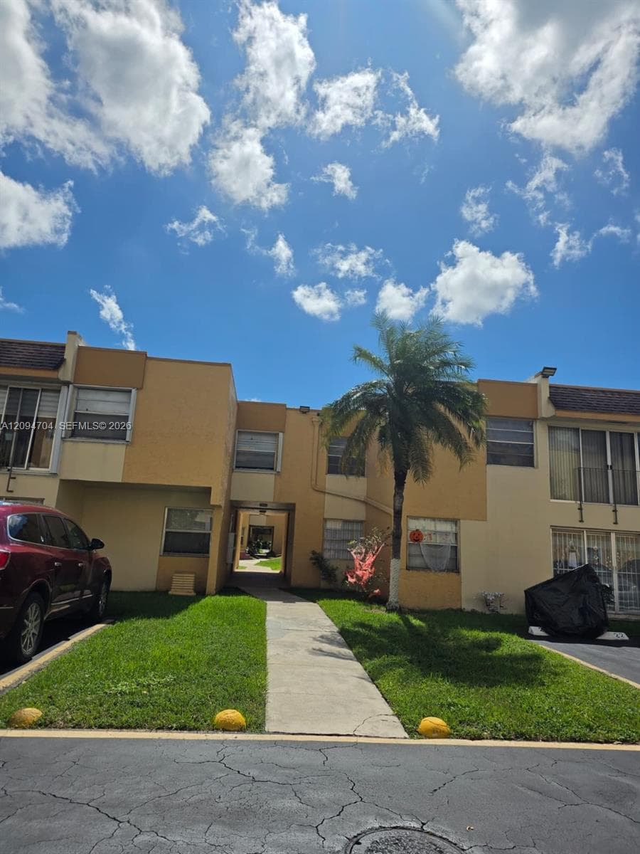 Multi-level exterior featuring a smooth stucco facade, concrete walkway, and mature palm tree