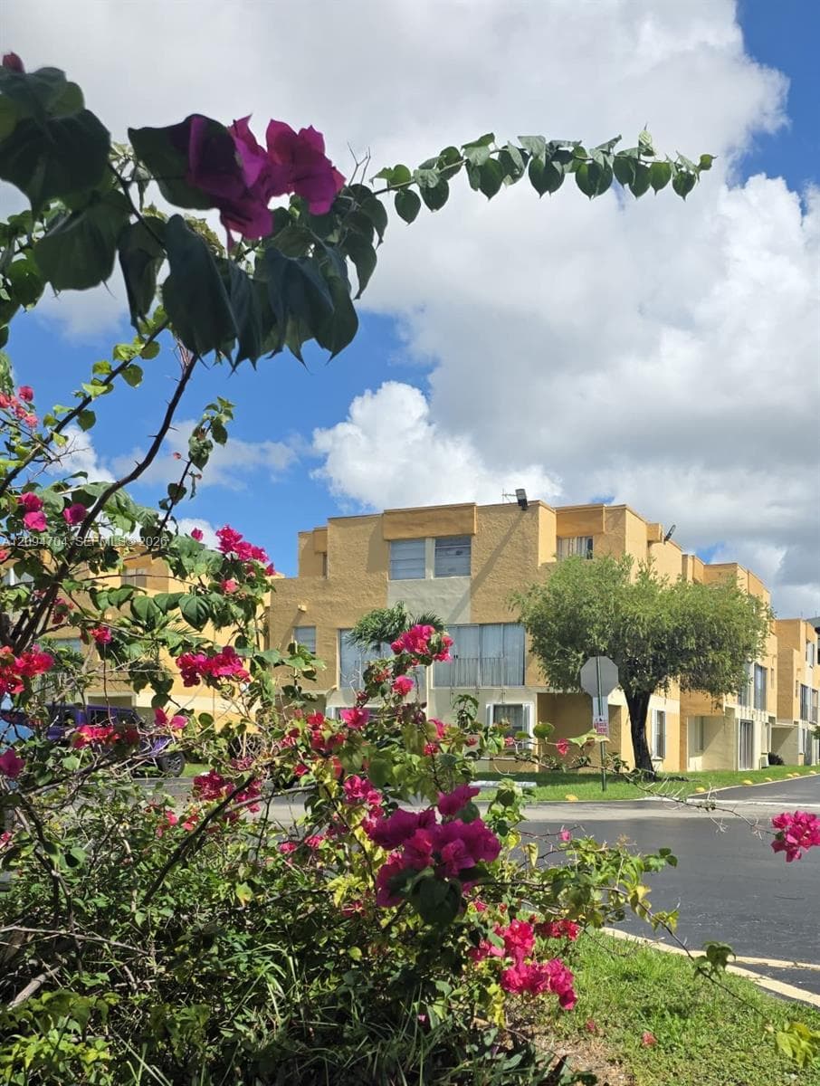 Multi-level stucco exterior featuring a textured facade, horizontal window groupings, and mature landscaping