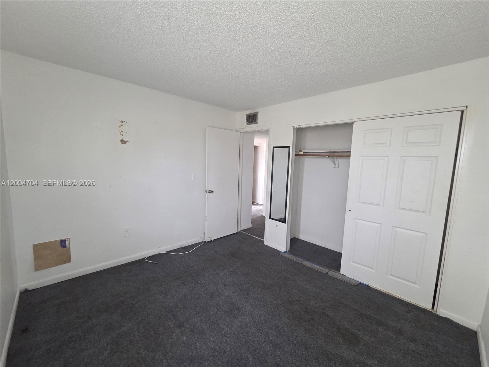Room featuring neutral wall finishes, grey carpeting, and a closet with double-panel doors