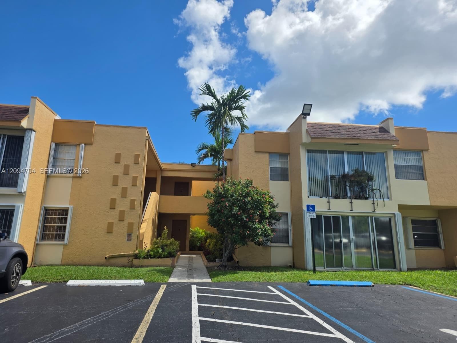 Stucco exterior featuring dual-level facade, sliding glass doors, horizontal windows, and palm tree landscaping