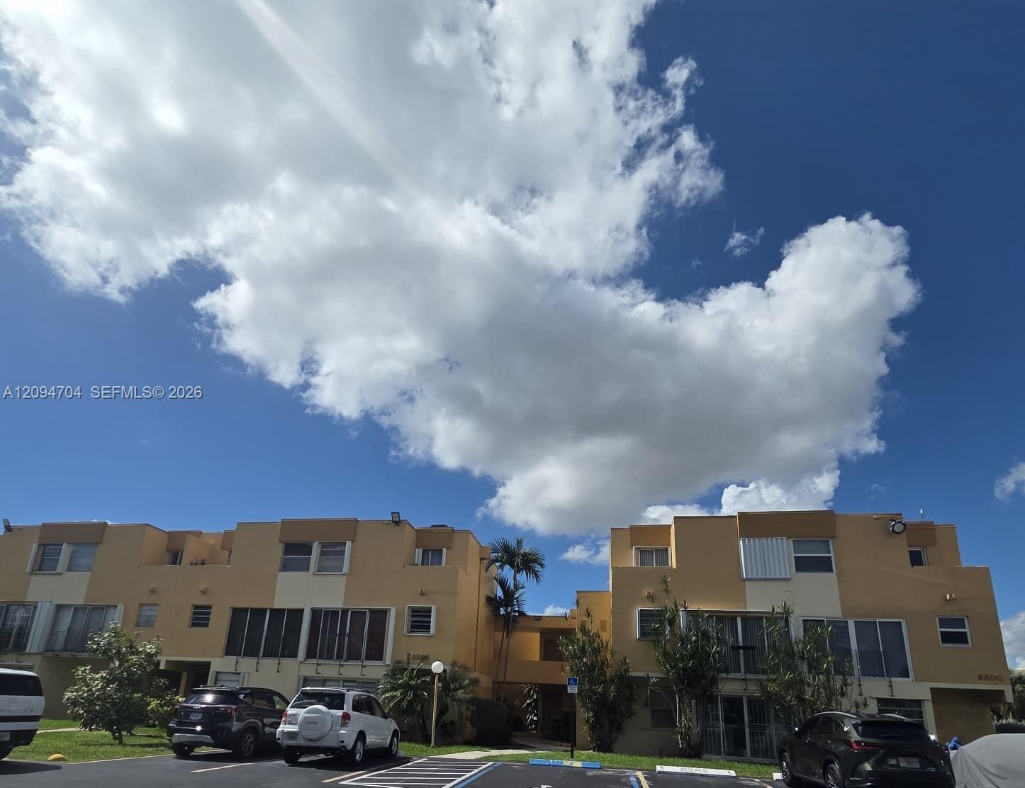 Multi-story stucco exterior featuring horizontal architectural accents, metal-frame windows, and integrated covered entrance walkways