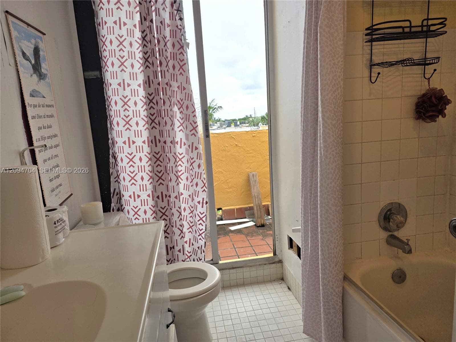Bathroom featuring square tile wall surround, standard soaking tub, integrated vanity sink, and sliding glass door with access to an exterior terrace
