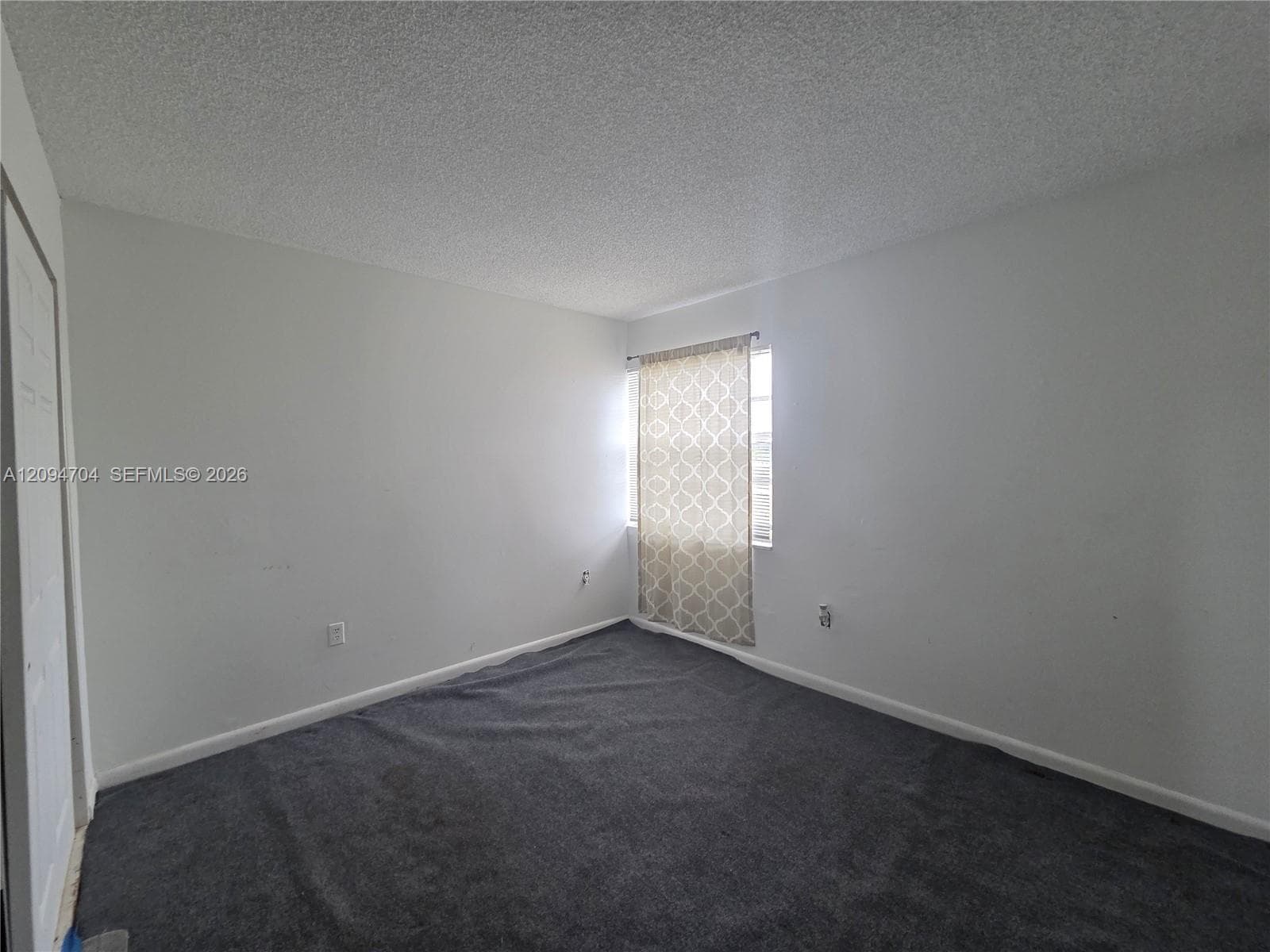 Interior space featuring neutral wall tones, gray carpeting, a window, and a multi-panel door
