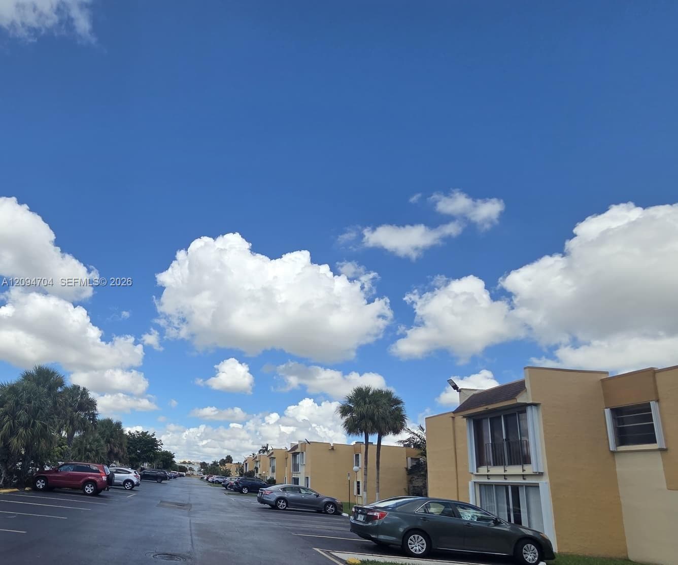 Multi-unit complex featuring stucco exterior walls, sliding glass windows, and asphalt parking area