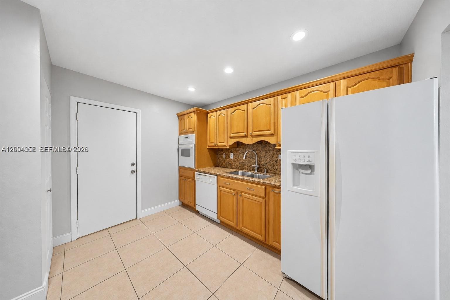 Kitchen featuring natural wood cabinetry, stone-finish countertops, tile flooring, recessed lighting, and built-in appliances