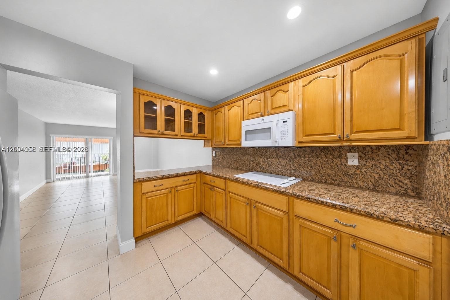 Kitchen featuring honey-tone cabinetry, stone-patterned countertops, built-in microwave, recessed lighting, and tile flooring