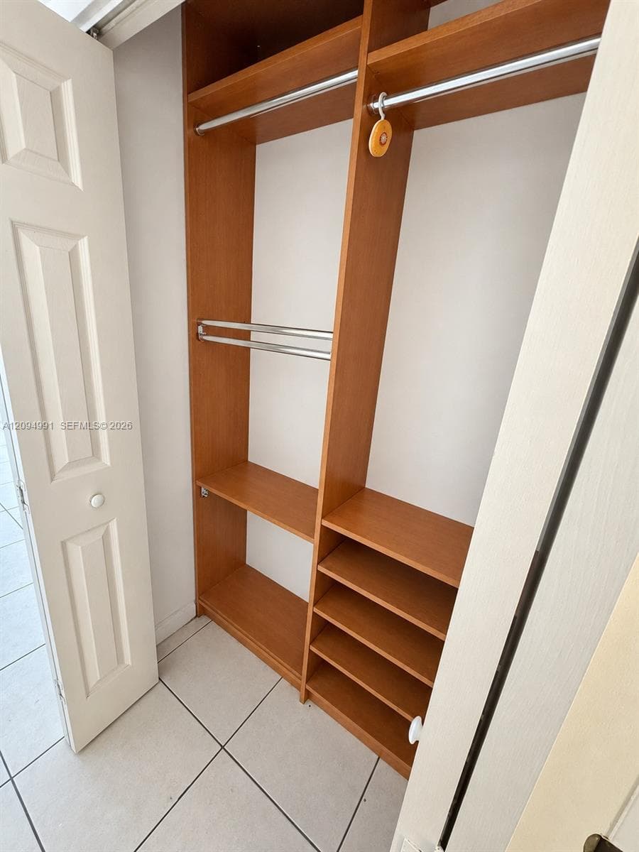 Built-in closet organizer featuring wood-finish shelving, multiple integrated storage cubbies, and dual-level metal garment rods