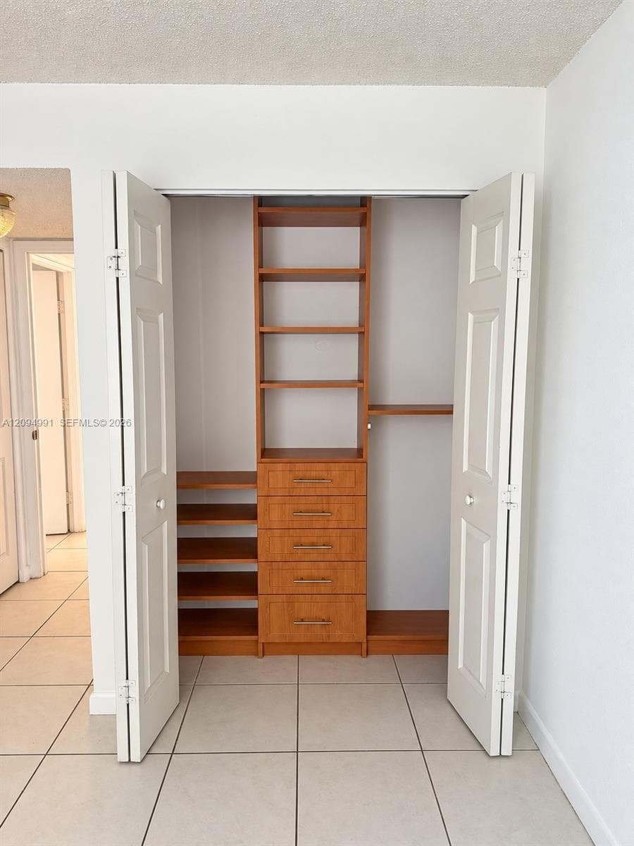 Built-in wooden closet system featuring open shelving, five storage drawers with metallic hardware, and white panel doors