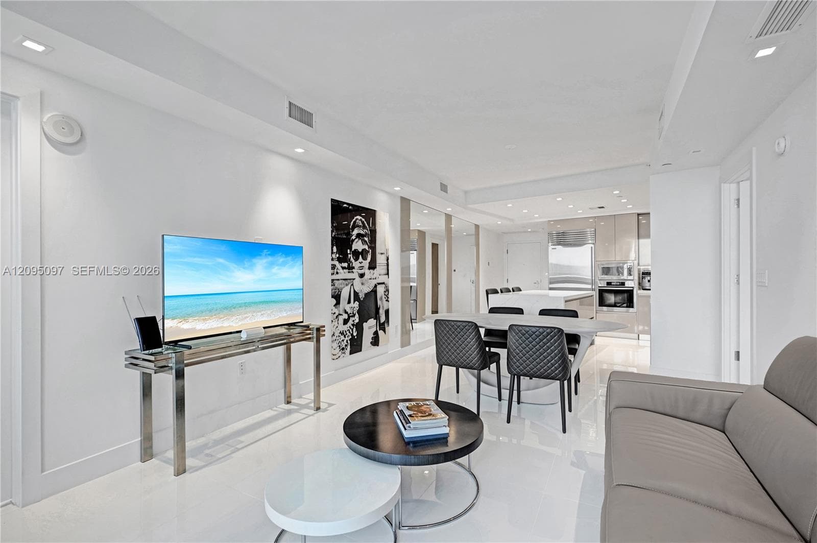Open-concept living space featuring high-gloss flooring, recessed lighting, integrated ceiling speakers, and kitchen cabinetry with a reflective finish