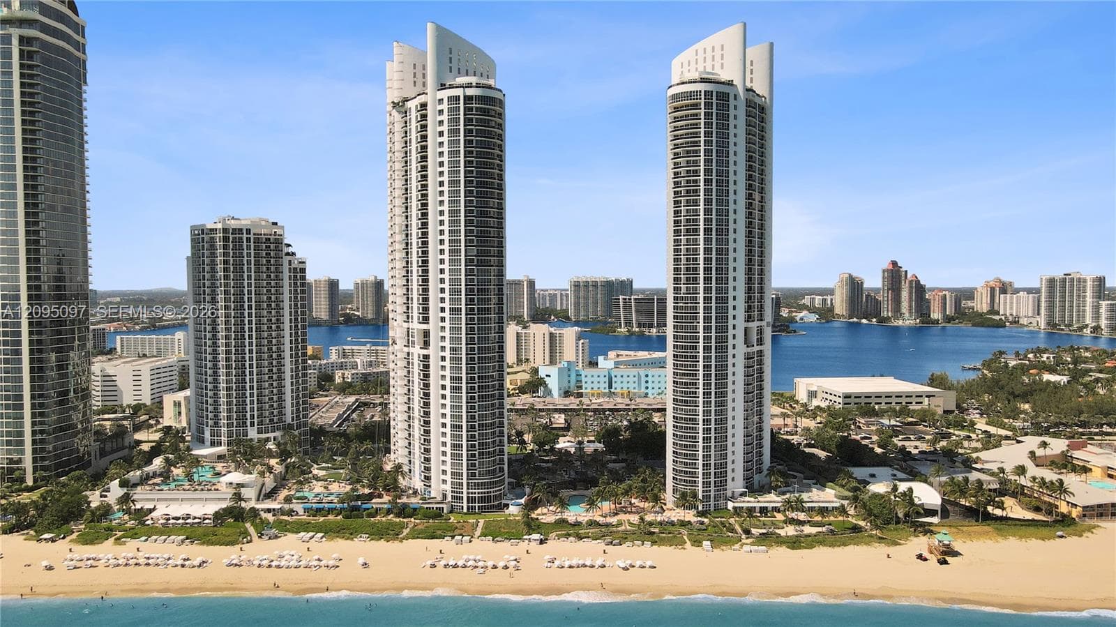 High-rise residential towers featuring glass-curtain facades, deep-set private balconies, and direct beachfront access with immediate proximity to coastal waterways