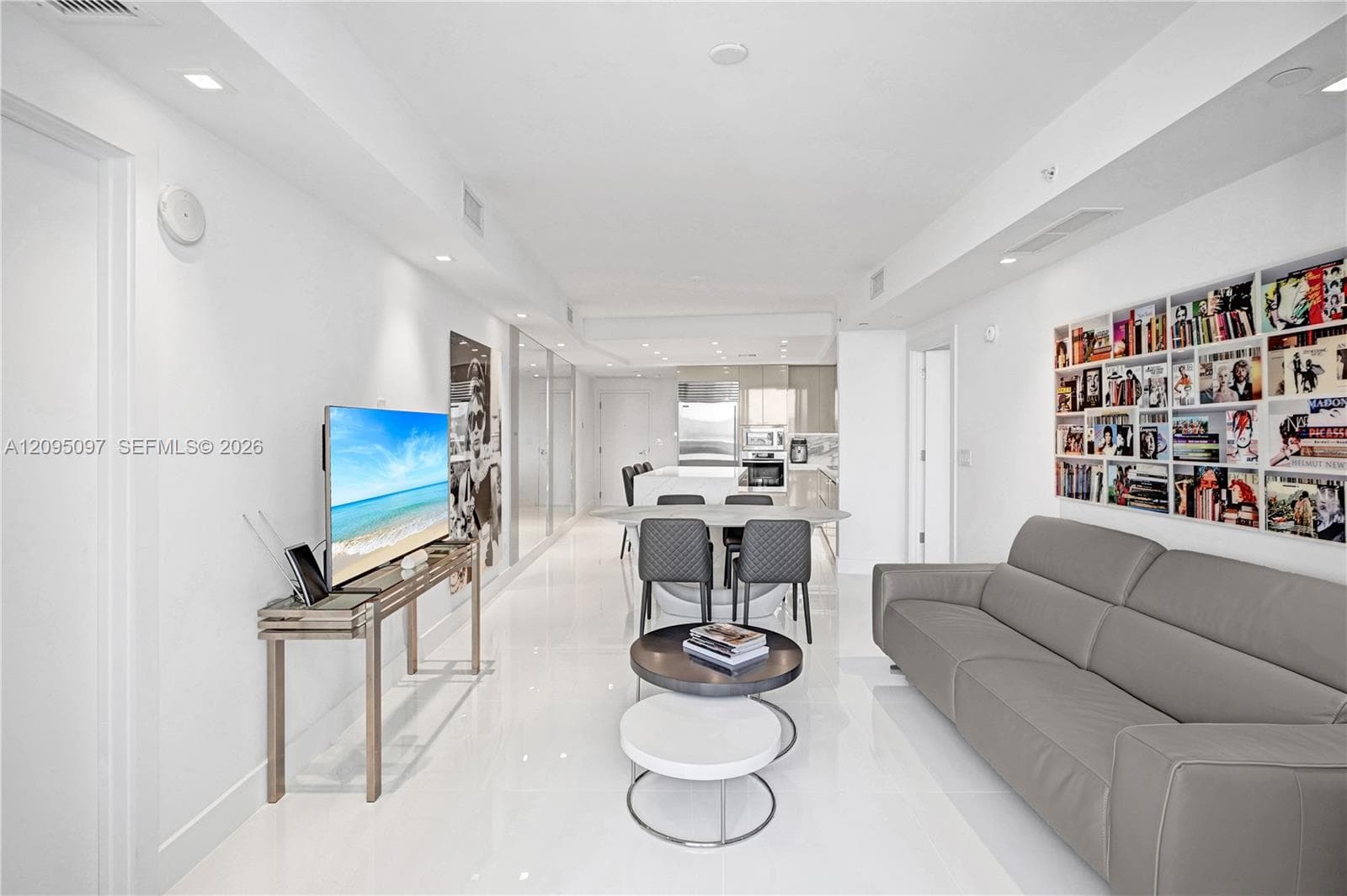 Open-concept interior featuring large-format polished tile flooring, recessed ceiling lighting, and custom built-in recessed shelving