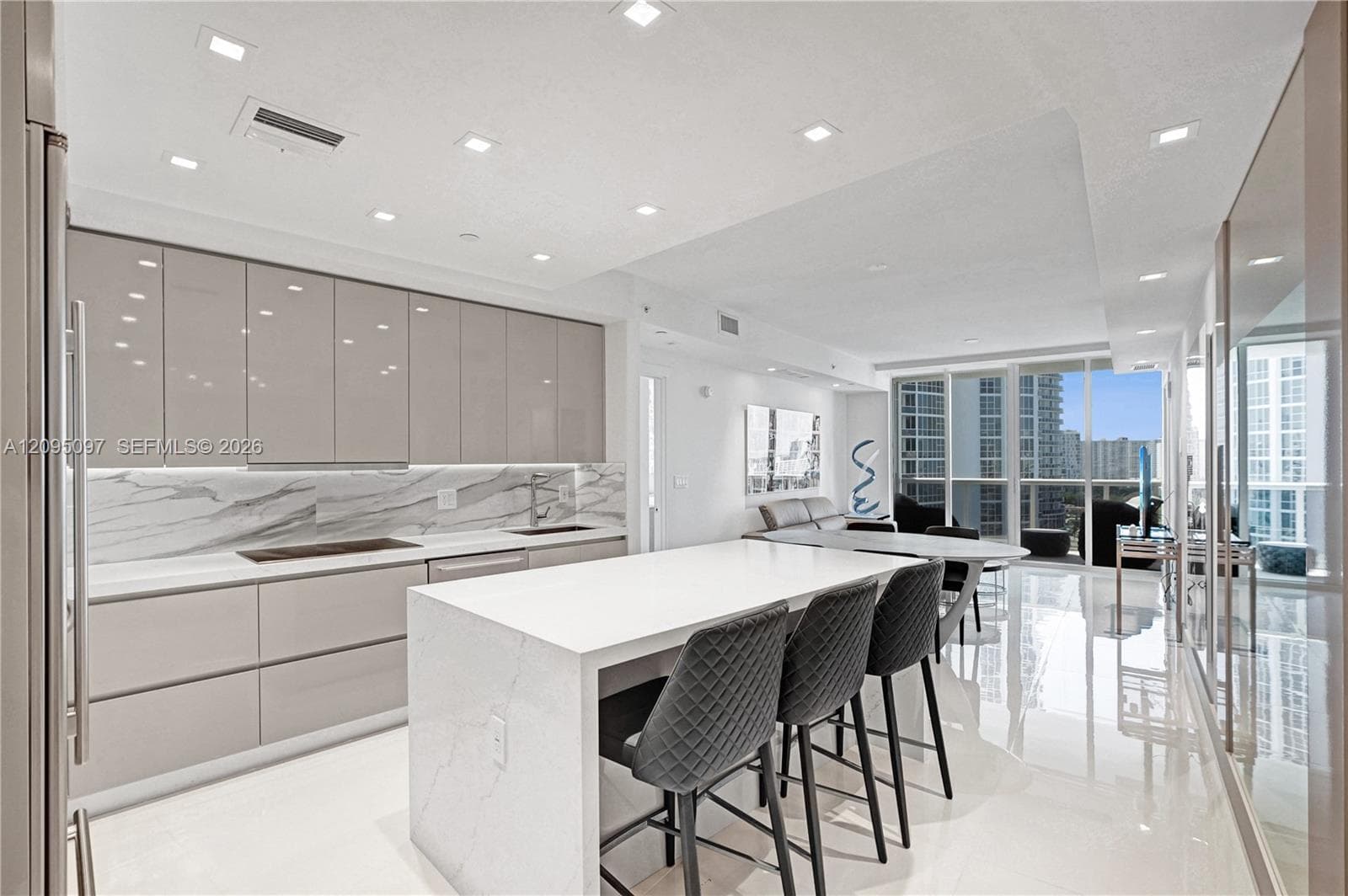 Contemporary kitchen featuring high-gloss cabinetry, a waterfall-edge stone island, stone-pattern backsplash, polished tile flooring, and recessed ceiling lighting