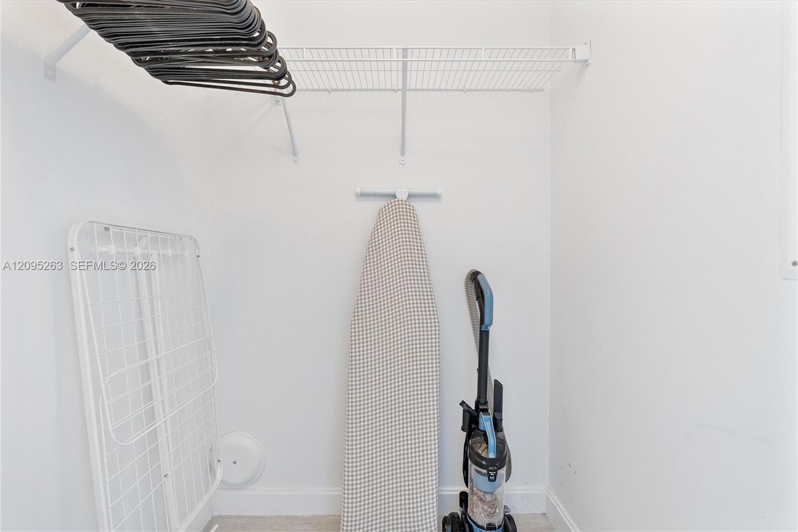 Storage space featuring white walls and a mounted wire shelving unit
