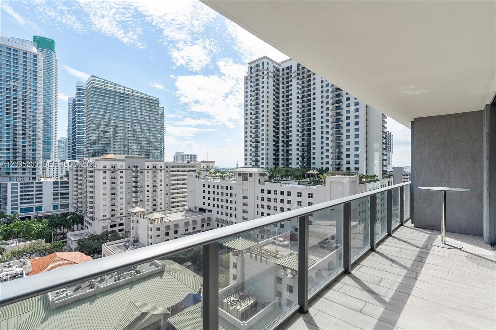 Covered balcony featuring tile flooring and a glass-paneled railing