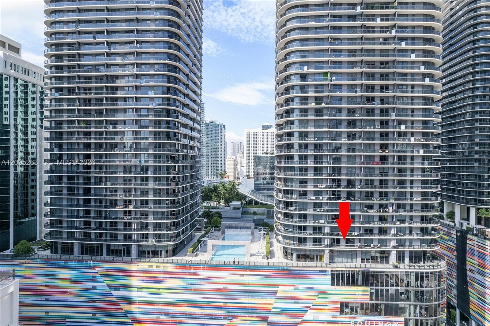 High-rise building featuring expansive wraparound balconies, floor-to-ceiling glass paneling, and an outdoor swimming pool facility