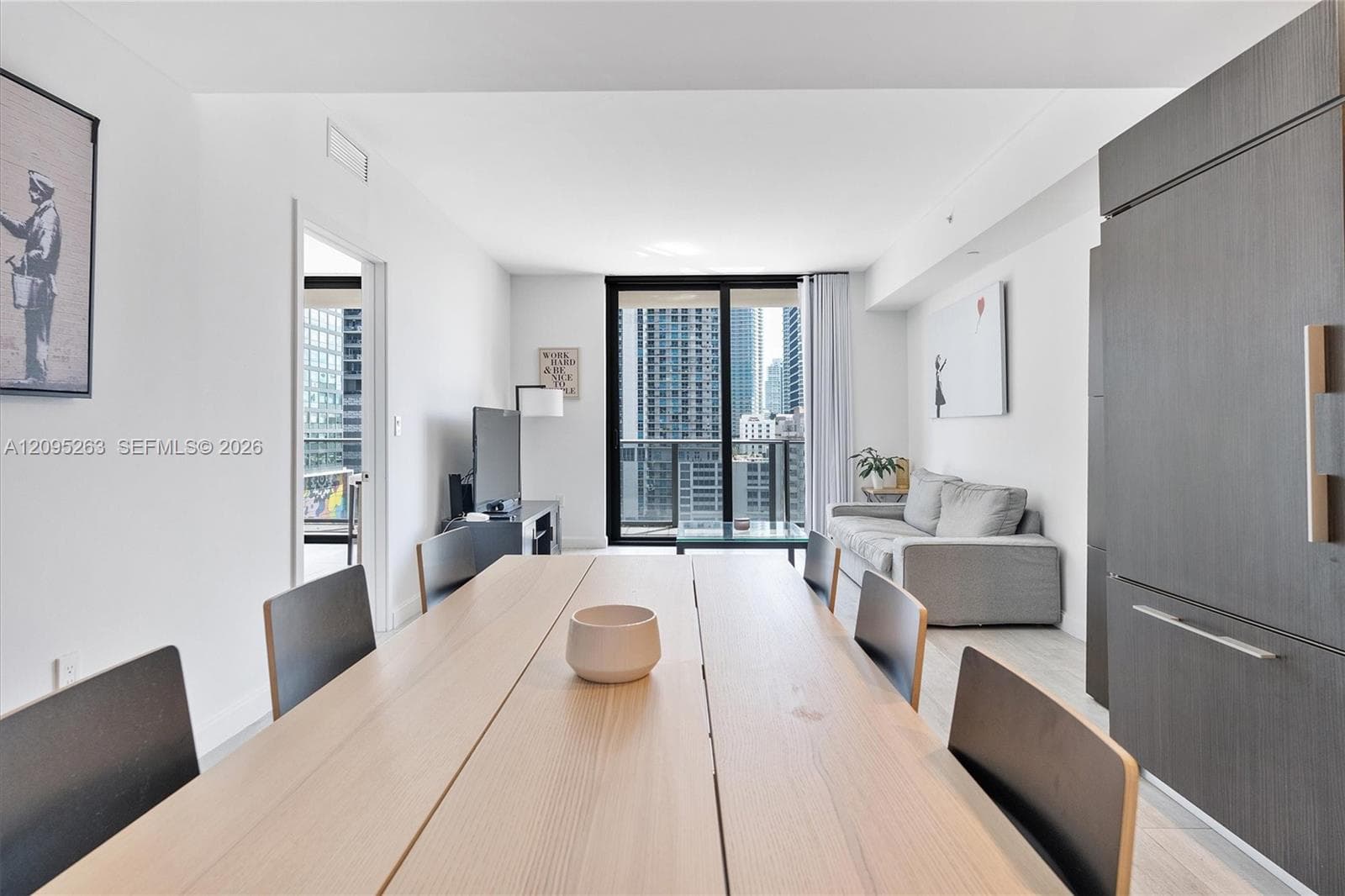 Open-concept space featuring floor-to-ceiling glass sliding doors, wood-finish flooring, and built-in cabinetry with integrated panel-ready refrigerator