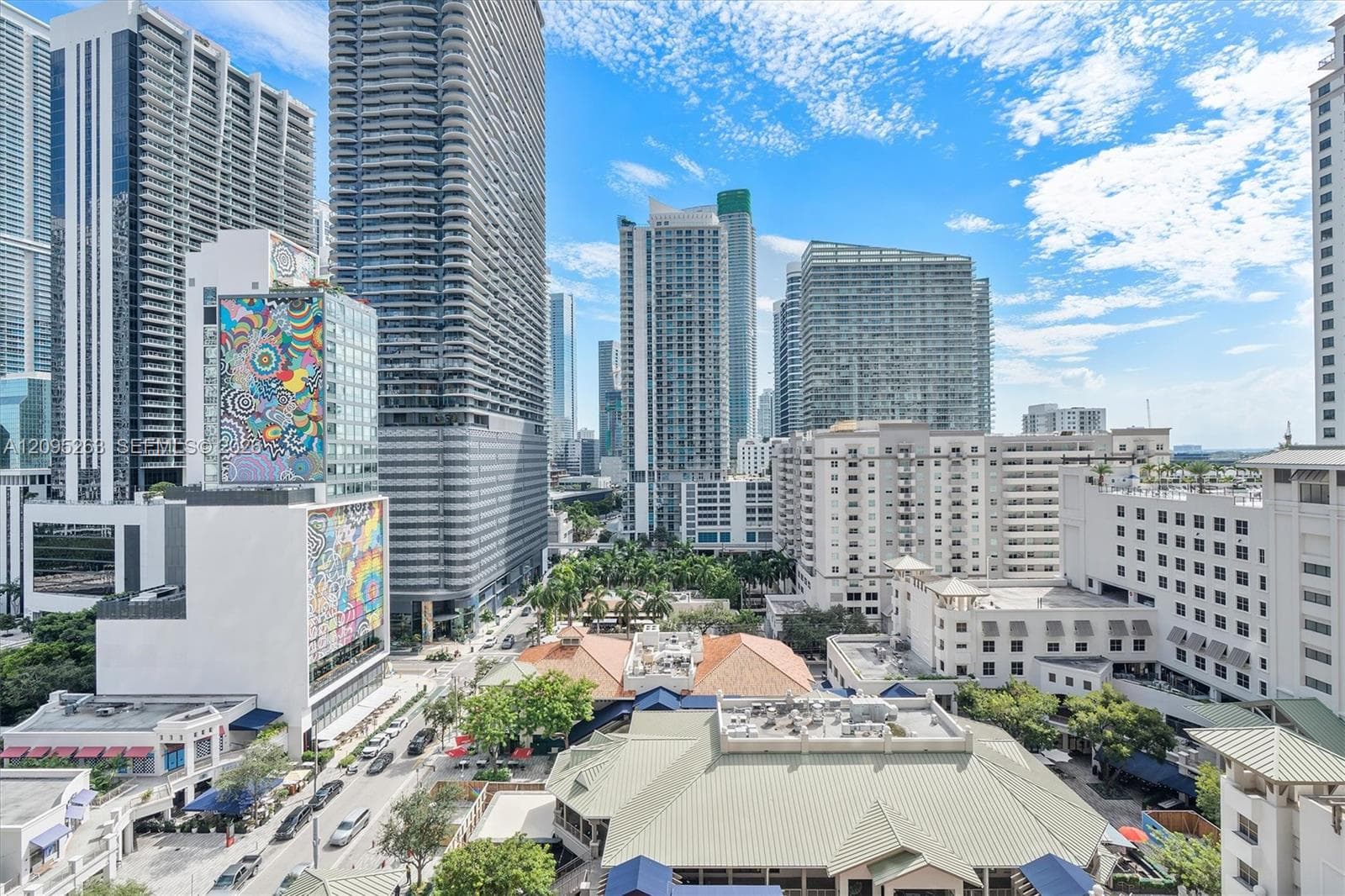 Urban landscape featuring high-rise architecture, mixed-use commercial buildings, and mature green canopy