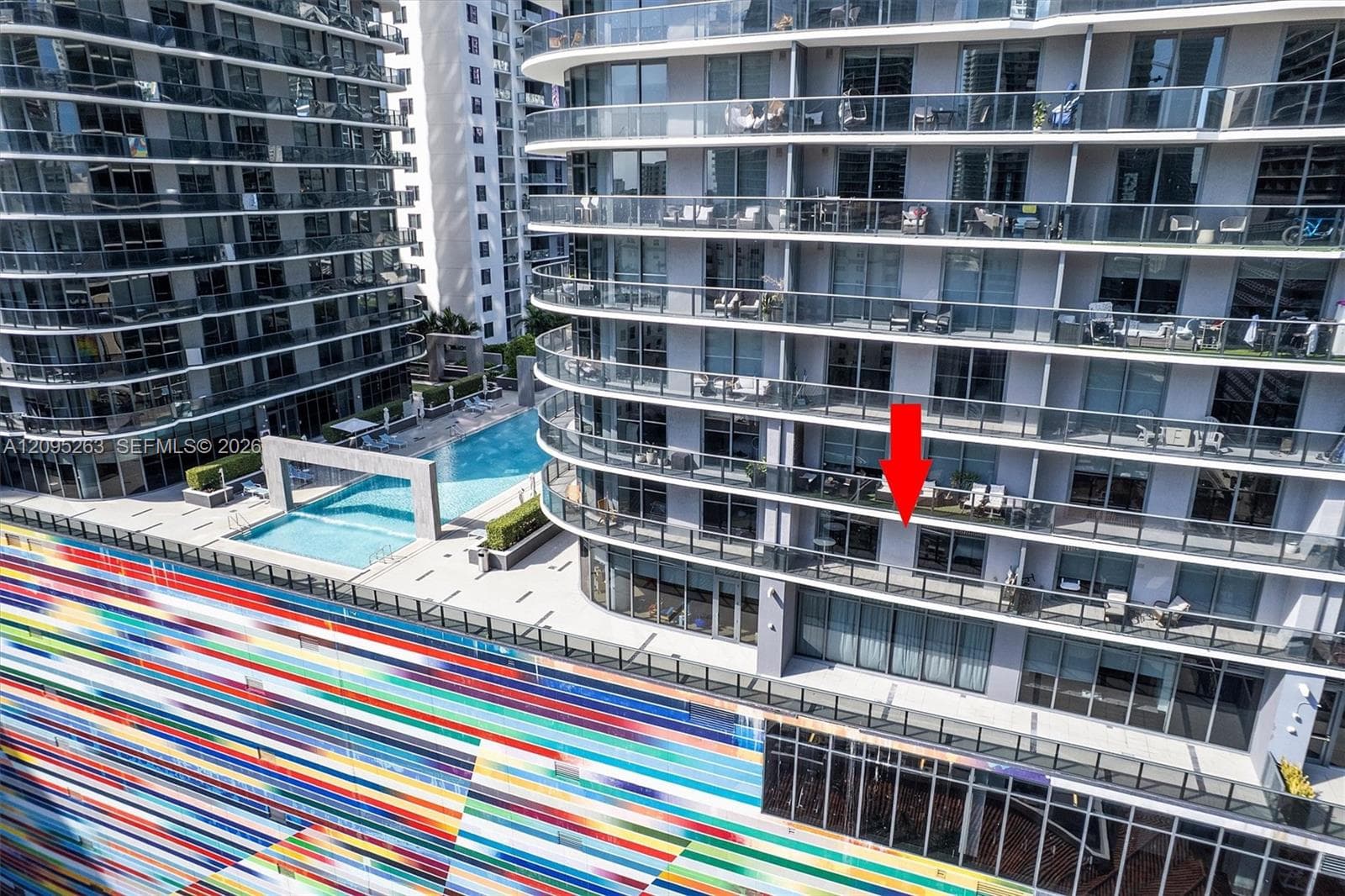 High-rise residential exterior featuring expansive private balconies with glass railings and access to an outdoor pool deck