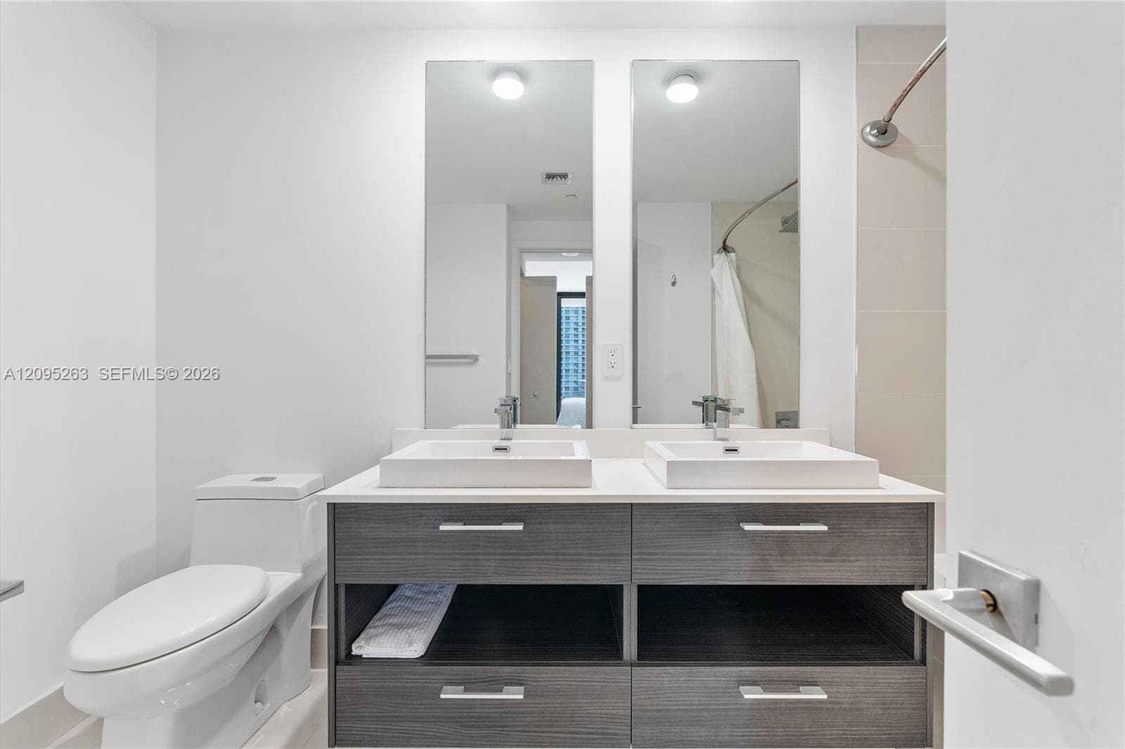 Dual-sink vanity with rectangular vessel basins, stone countertop, wood-finish cabinetry, and two full-length mirrors