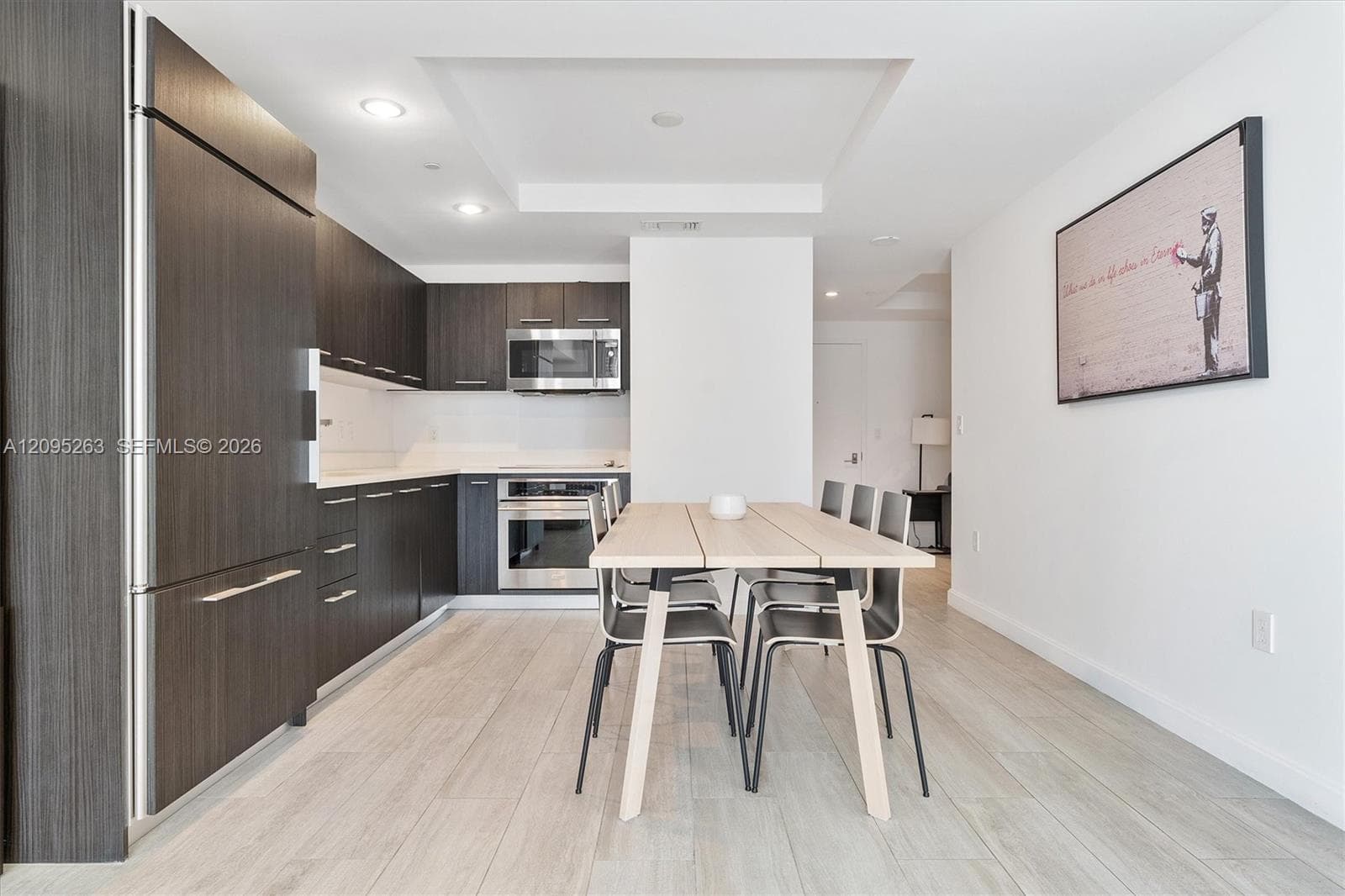 Kitchen featuring dark-toned cabinetry, stainless steel appliances, recessed ceiling lighting, and light-toned wood-finish flooring