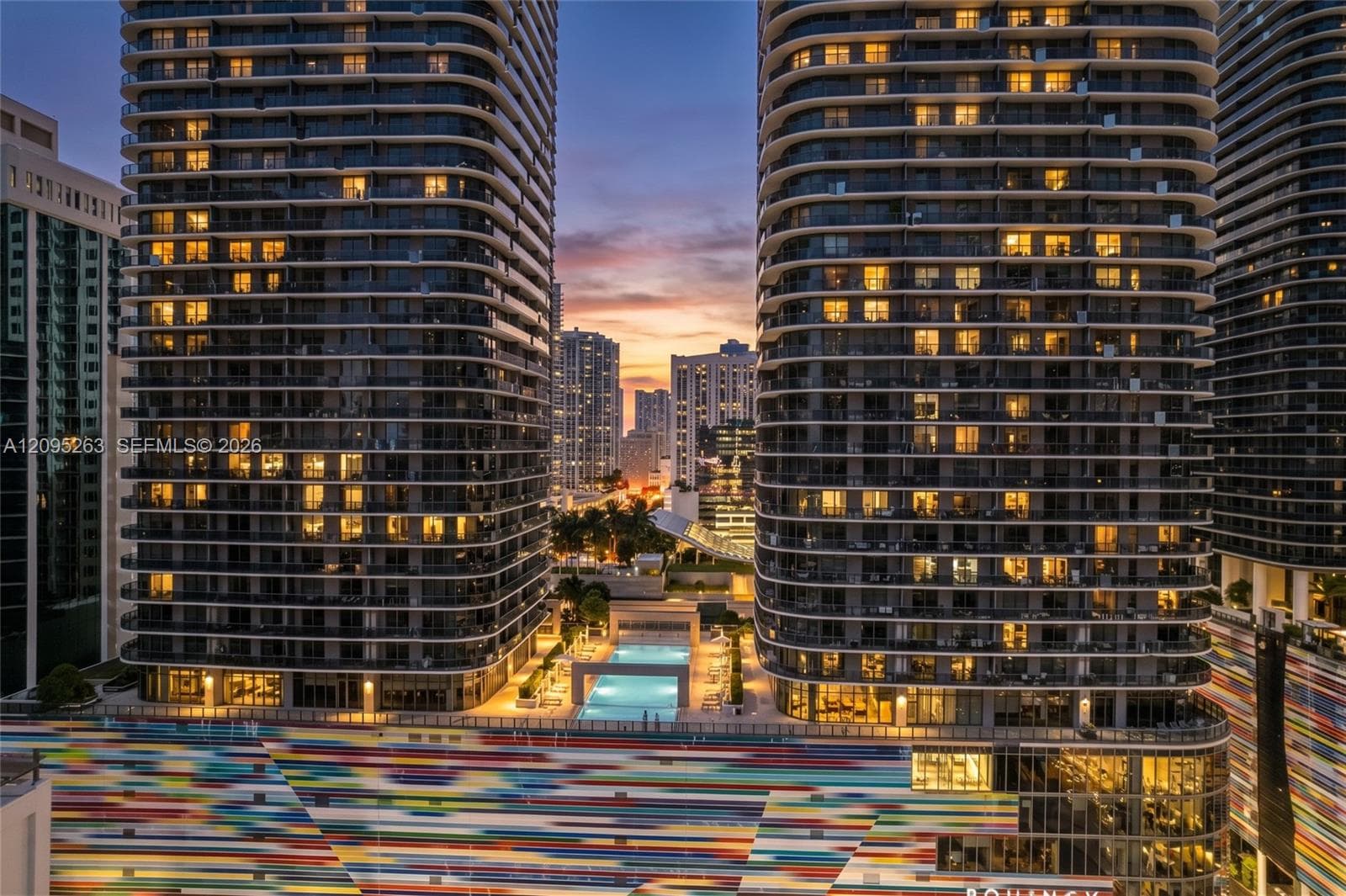 Virtual Twilight High-rise towers featuring wrap-around glass balconies, an outdoor swimming pool, and geometric architectural design elements
