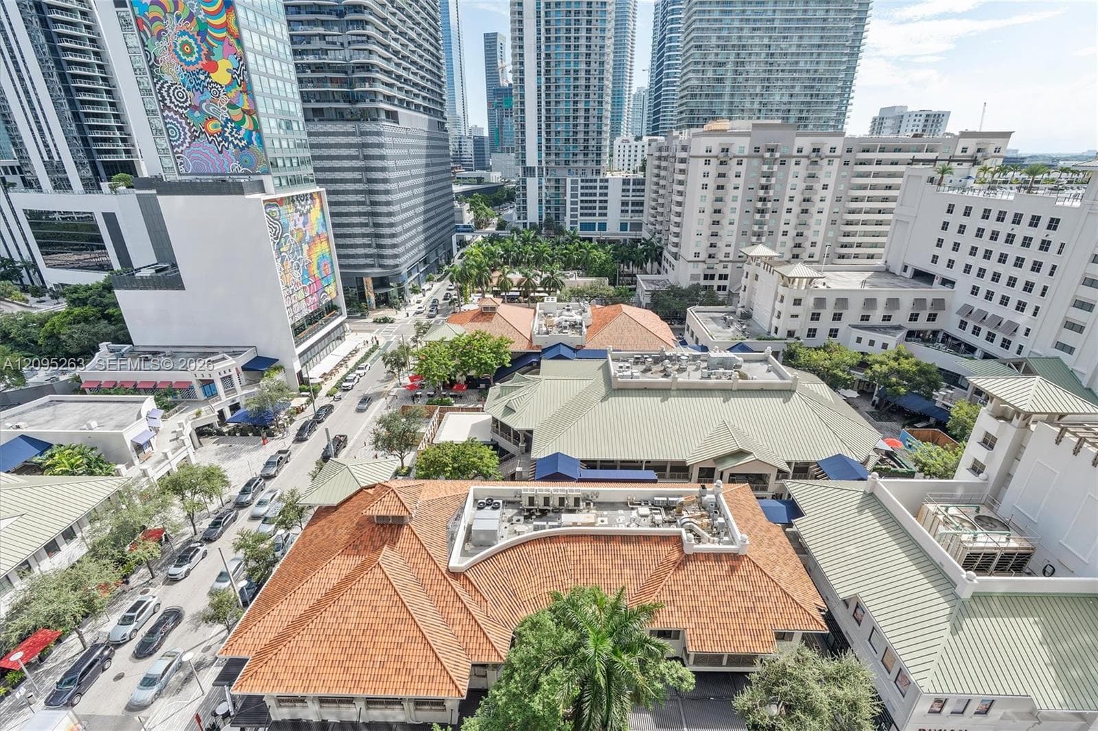 Urban aerial perspective featuring multi-story high-rise architecture, terracotta-tiled rooflines, and mature palm vegetation within a metropolitan setting