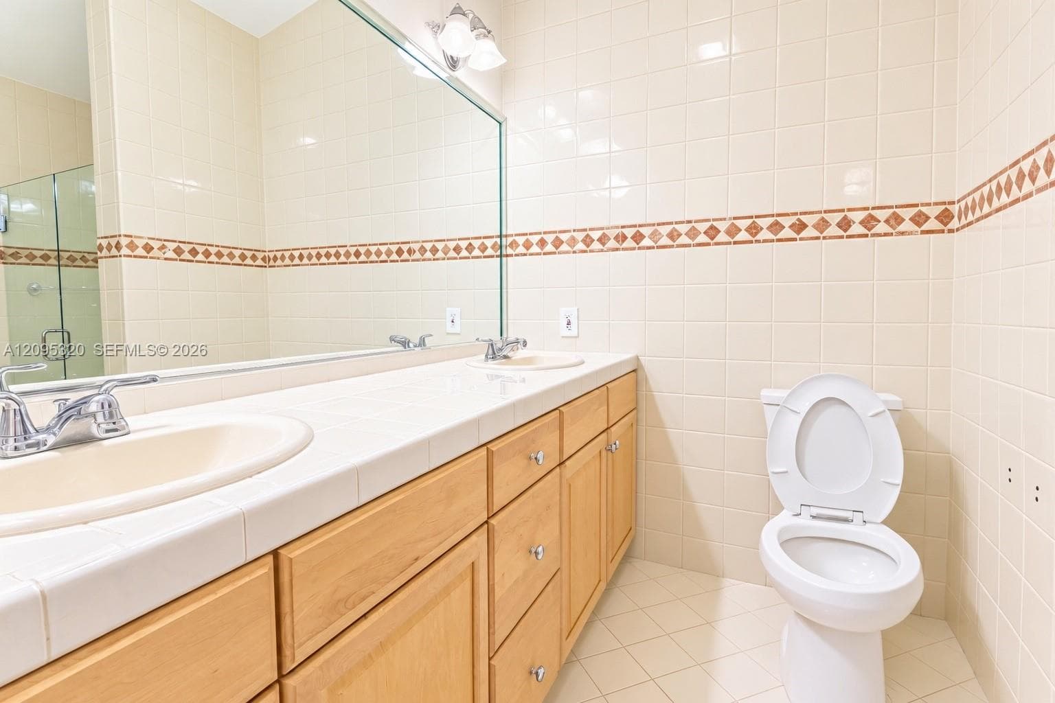 Dual vanity with integrated sinks, wood-finish cabinetry, and a full-width mirror
