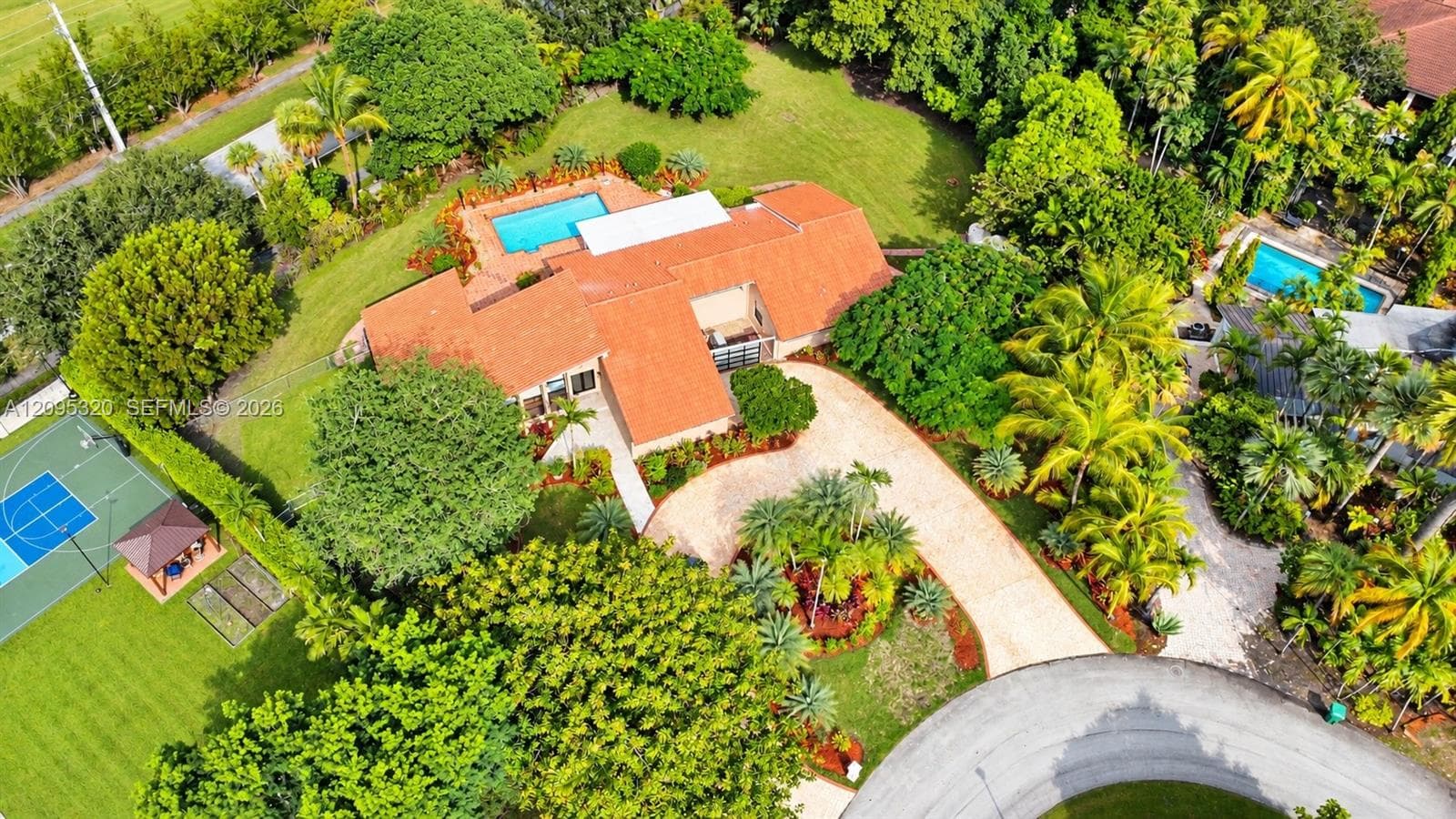 Expansive property featuring a red tile roof, two swimming pools, a tennis court, a gazebo, and a long curved driveway