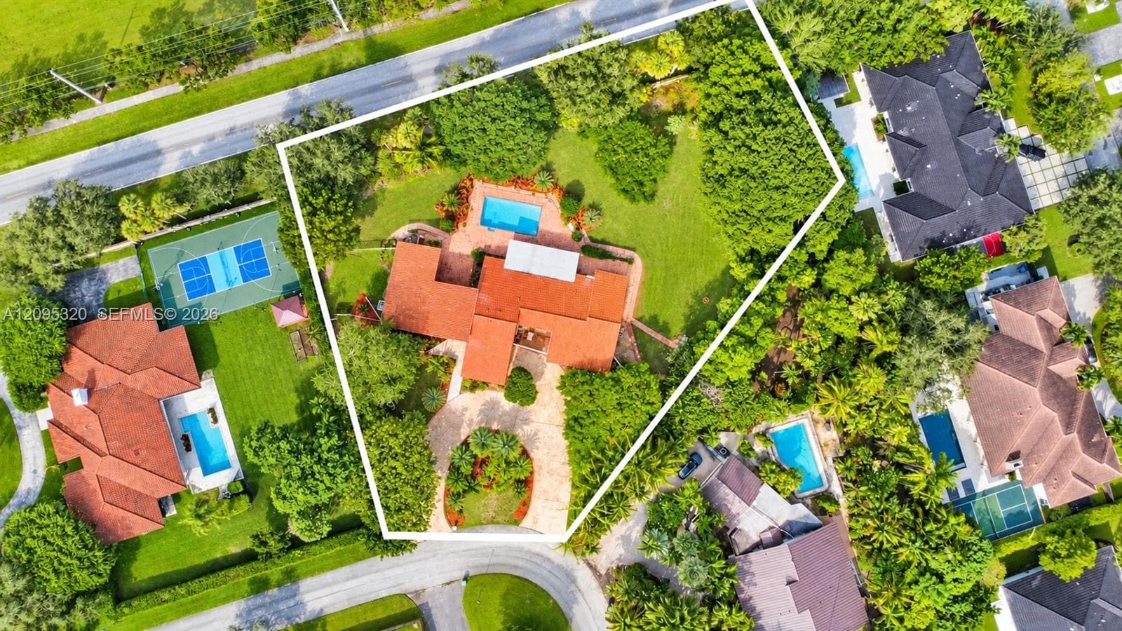Expansive property featuring a swimming pool, mature trees, manicured lawn, and a paved circular drive
