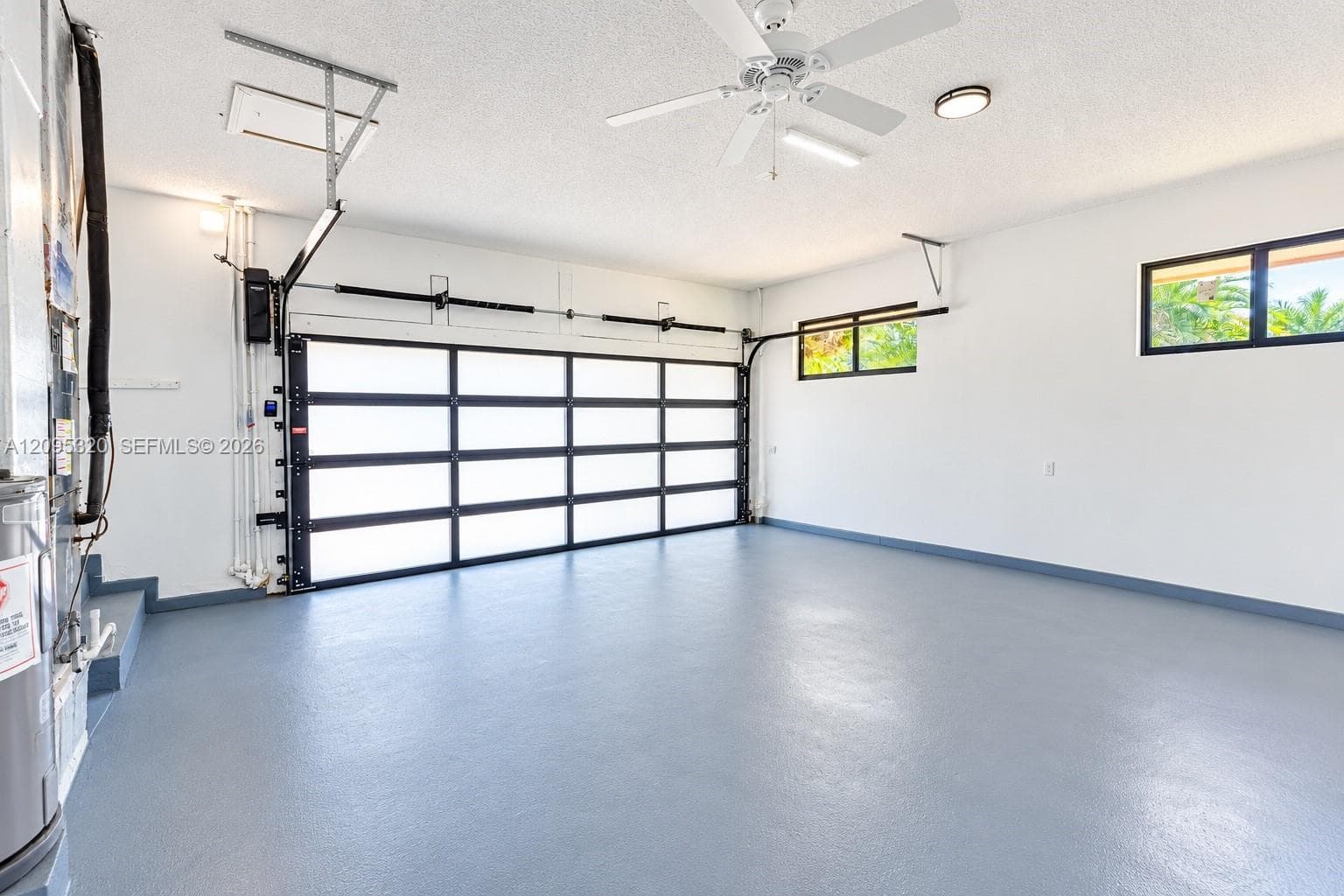 Garage featuring a full-light panel door, epoxy floor, ceiling fan, and multiple windows